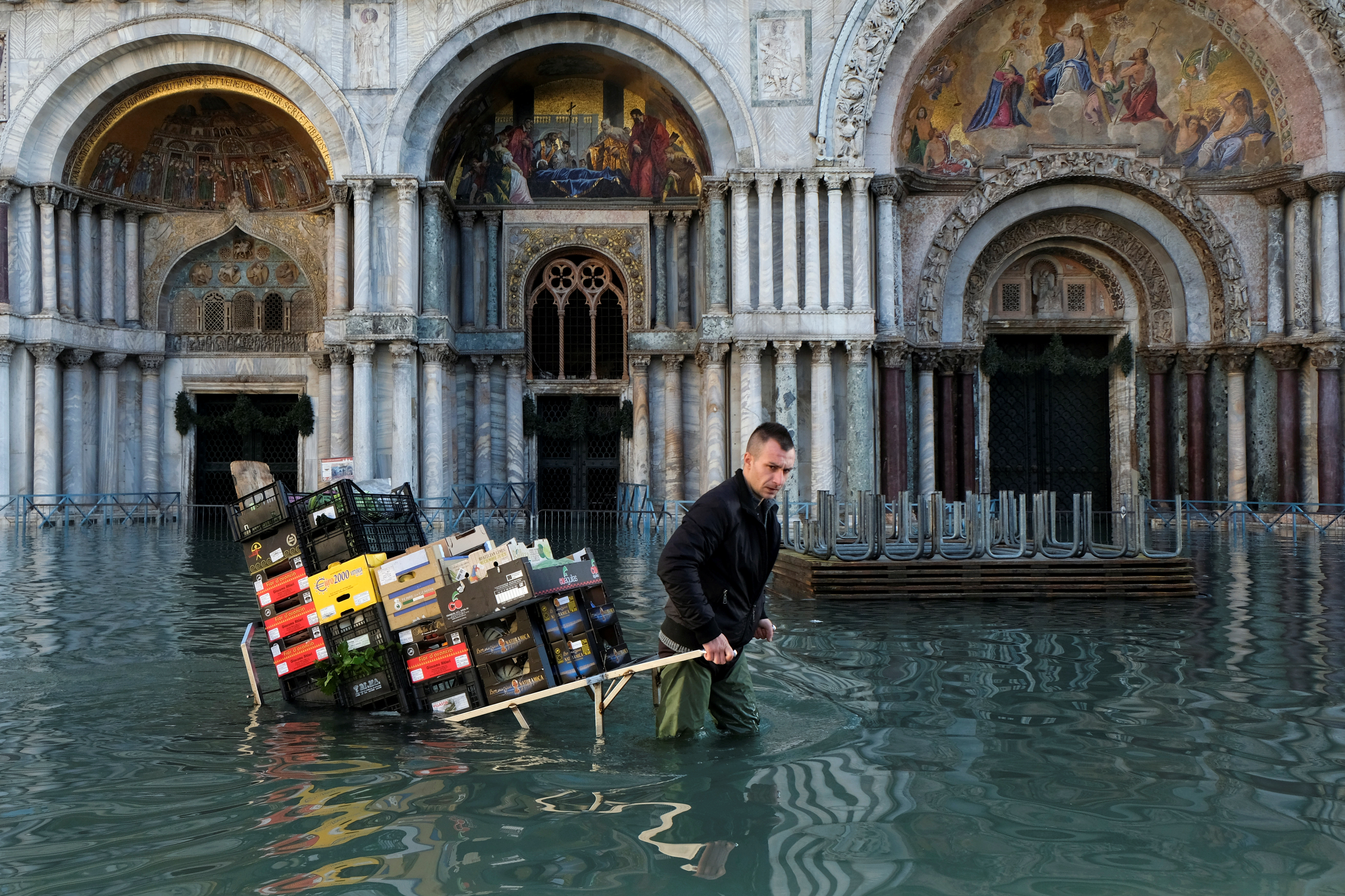 Un hombre tira de un carro que transporta frutas y verduras a través de la inundada Plaza de San Marcos (REUTERS/Manuel Silvestri)