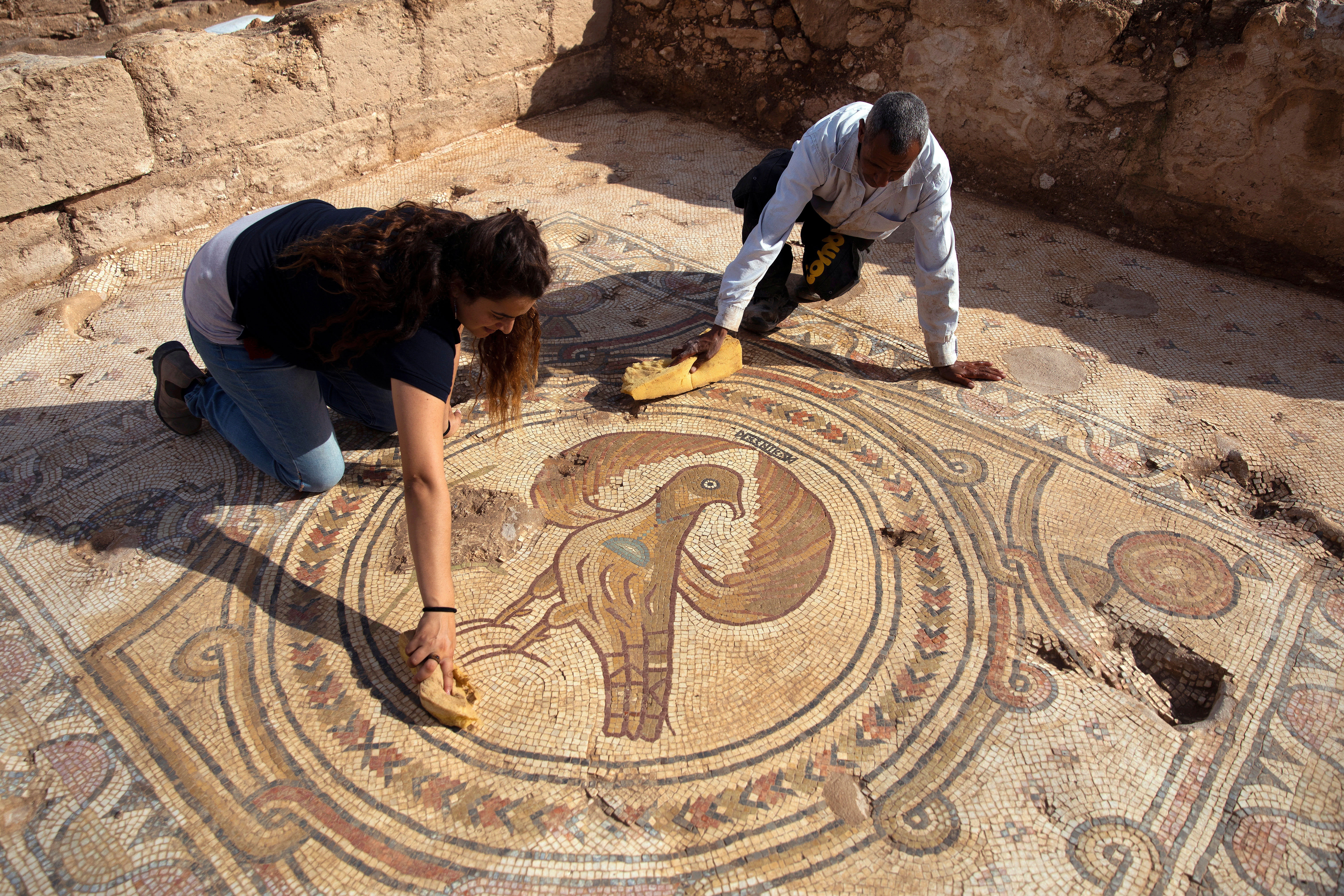 Dos trabajadores de la Autoridad de Antigüedades de Israel limpian el piso de mosaico donde se puede ver la "Águila Imperial", un símbolo típico de la cultura bizantina. (REUTERS / Ronen Zvulun)