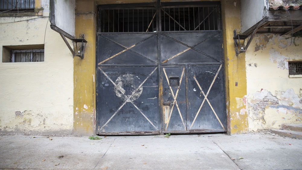 Una puerta de doble hoja ya azulada por el tiempo sobre calle Pichincha es el acceso principal. Todavía quedan los contornos de los escudos en los que hasta hace poco se leía: