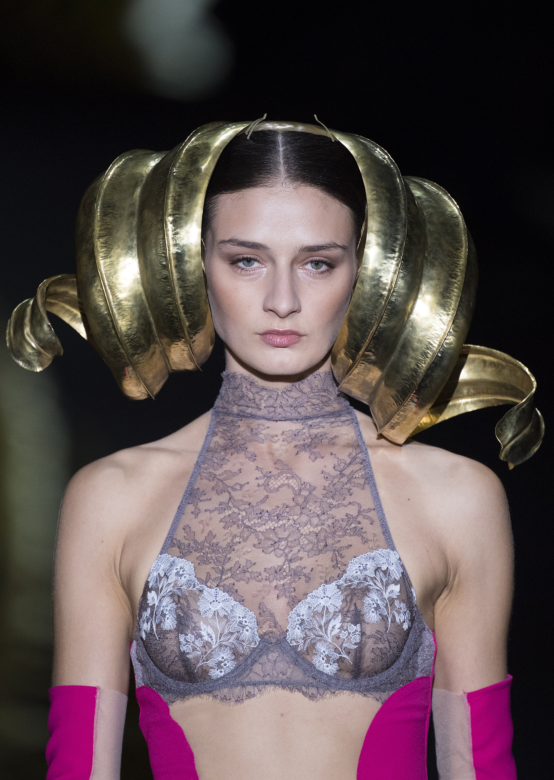 Andrés Sardá presentó un brasier de encaje de cuello halter y aro. ¿Lo extravagante? El estilismo del look. Un casquete dorado de orejas onduladas y guantes y corsé fucsias