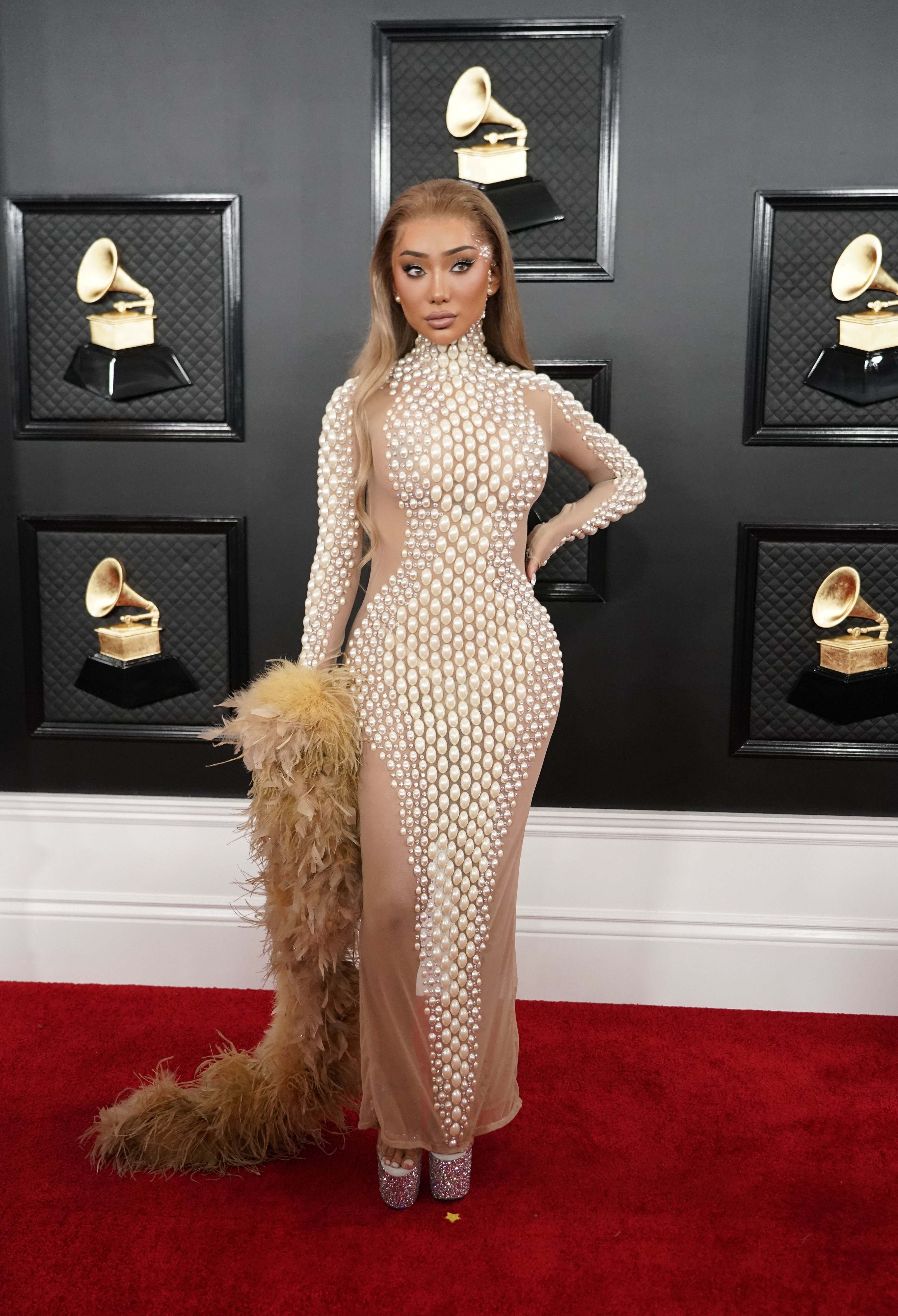 Nikita Dragun - "Se mostró con un vestido polera al cuerpo, con pedrería e ilusión óptica con transparencia en los laterales, con boa de Plumas", opinó a Infobae Gaby Gurmandi, asesora de imagen. Por su parte, Laura Malpeli de Jordaan, asesora de imagen, directora de Styletto opinó: "Nikita Dragun nos muestra como los tonos neutros no implican que el atuendo sea clásico. Los detalles perlados que agregan brillo y generan una silueta curvilínea se suman a los metalizados en las plataformas del calzado y en su maquillaje"