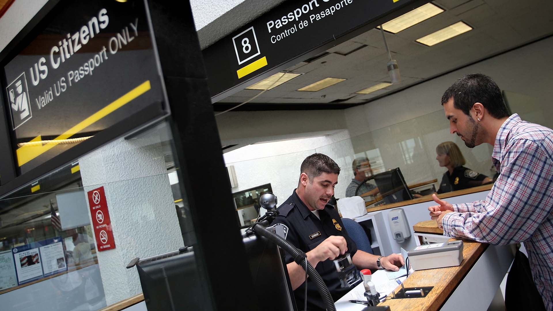 Un oficial de Aduanas y Protección Fronteriza revisa los pasaportes en la cabina de control de pasaportes cuando las personas ingresan a los Estados Unidos a través del Aeropuerto Internacional de Miami el 22 de junio de 2007 en Miami, Florida. (Photo by Joe Raedle/Getty Images)