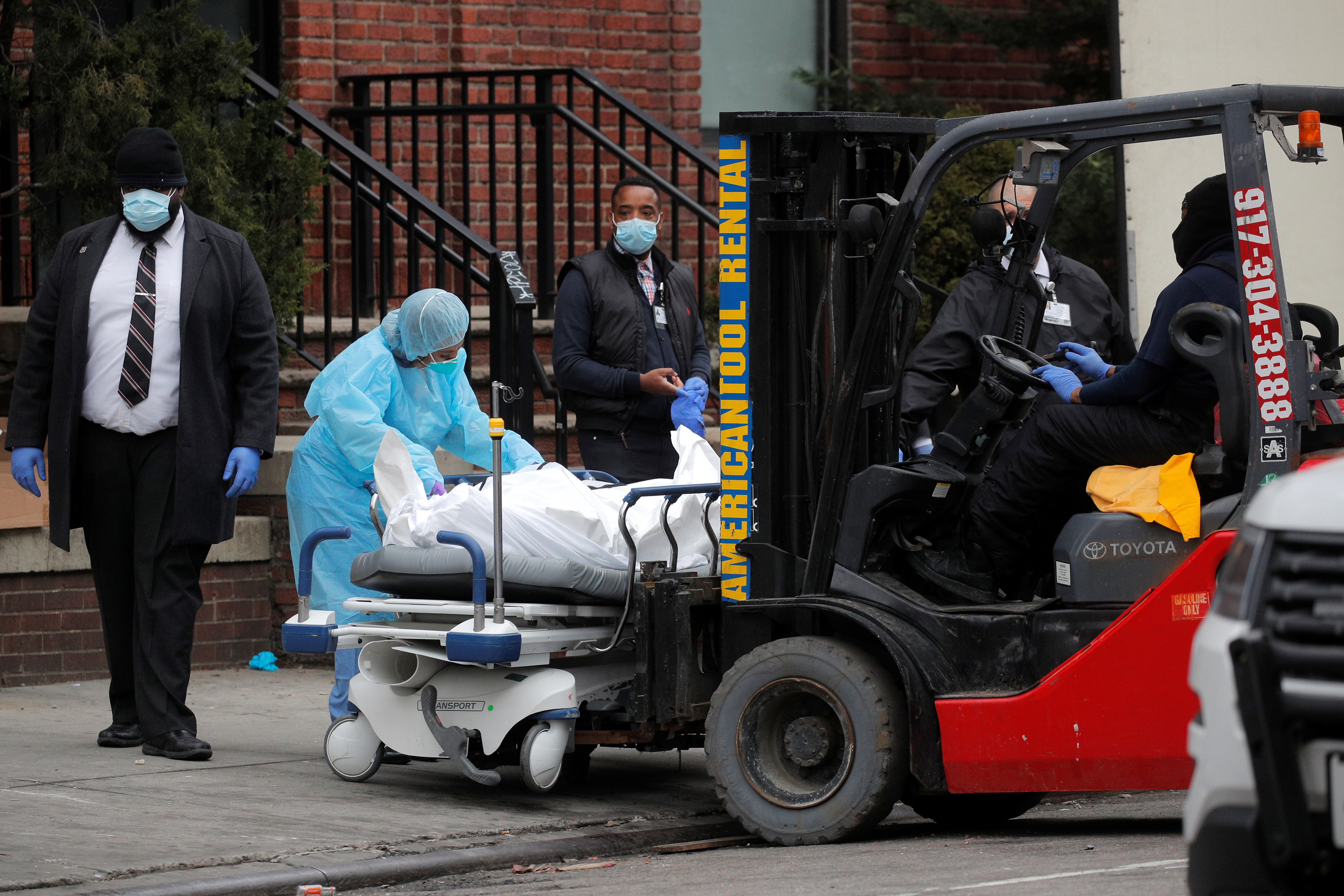 Un grupo de trabajadores se prepara para cargar a una persona fallecida en un remolque afuera del Centro Hospitalario de Brooklyn, Nueva York (REUTERS/Brendan Mcdermid)