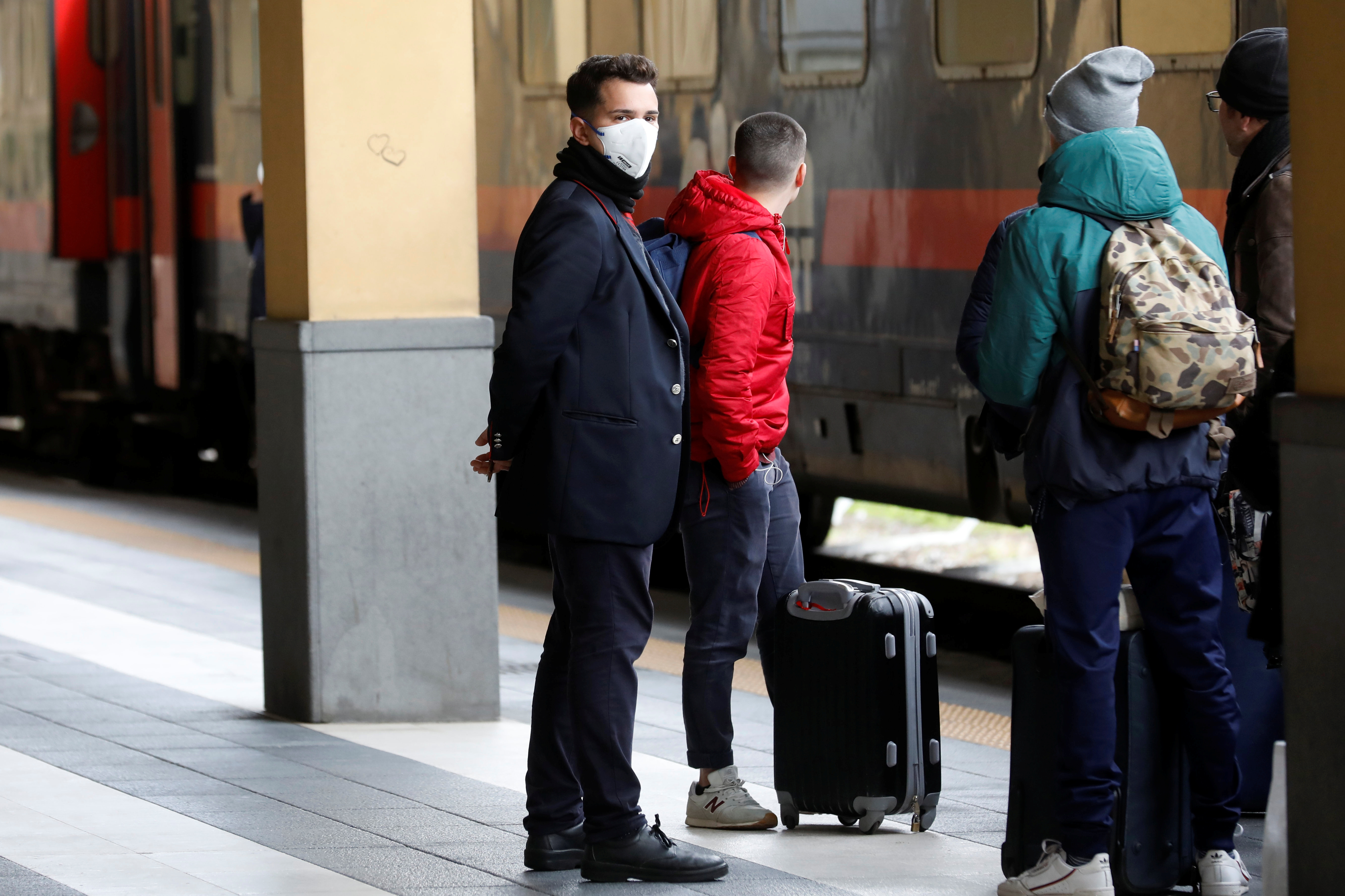 Pasajeros con barbijos en la estación de Catania, Sicilia, bajan de un tren que ha llegado desde Milán, una ciudad que ahora está cerrada bajo llave después de que el gobierno decretó una zona masiva prohibida establecida para contener el brote de coronavirus (REUTERS / Antonio Parrinello)