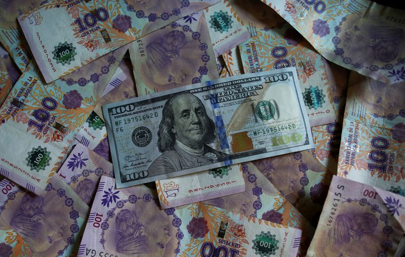 Foto de archivo. Fotografía ilustrativa. Billetes de 100 pesos argentinos debajo de un billete de 100 dólares estadounidenses (REUTERS/Agustin Marcarian)