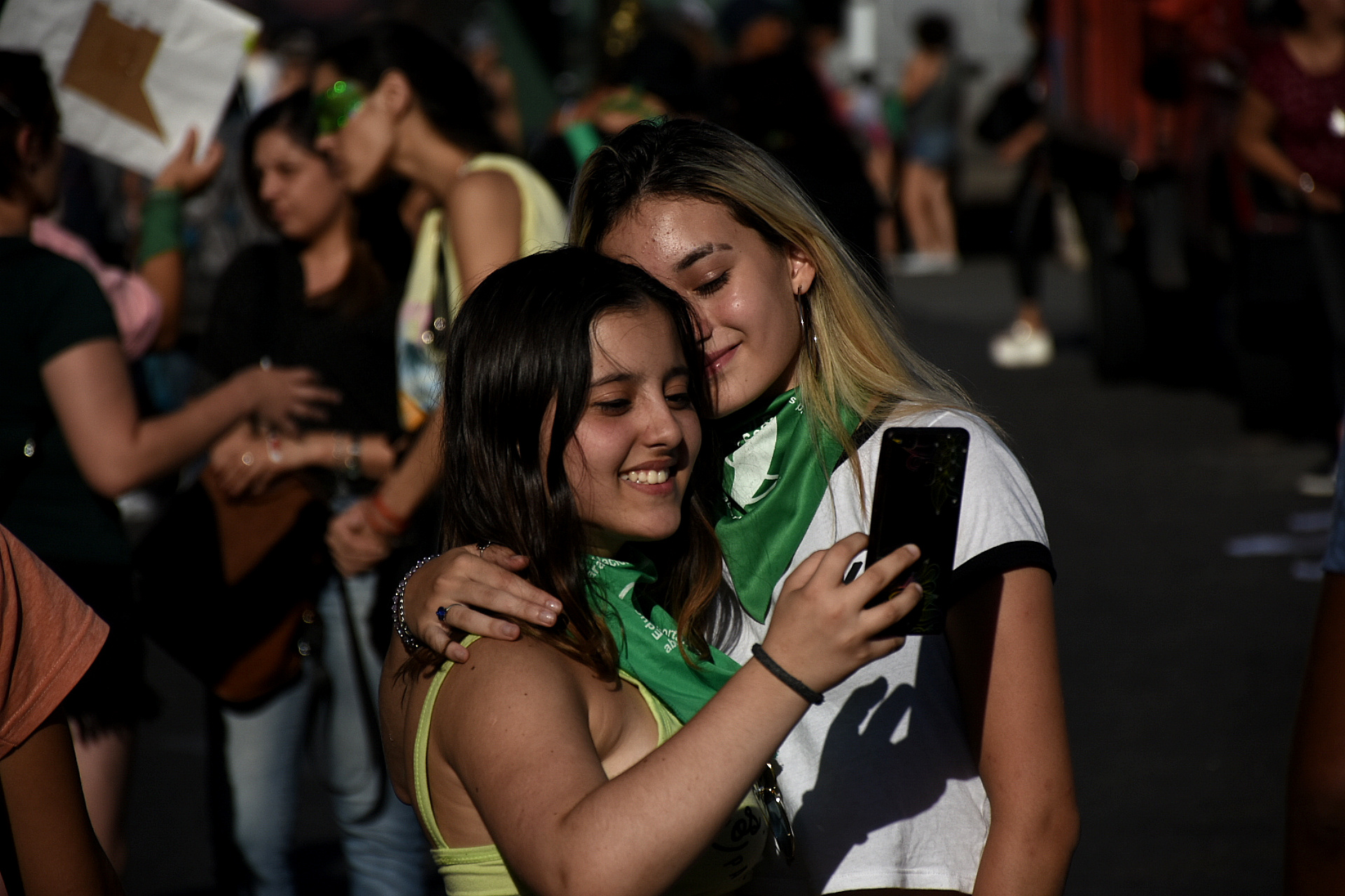 Dos jóvenes posan para una selfie con el pañuelo verde
