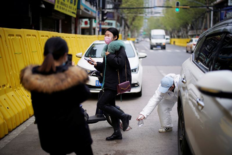 Un conductor con un traje protector desinfecta a una mujer en una calle de Wuhan, provincia de Hubei, el epicentro del brote de la enfermedad coronavirus de China (COVID-19), el 3 de abril de 2020. REUTERS/Aly Song