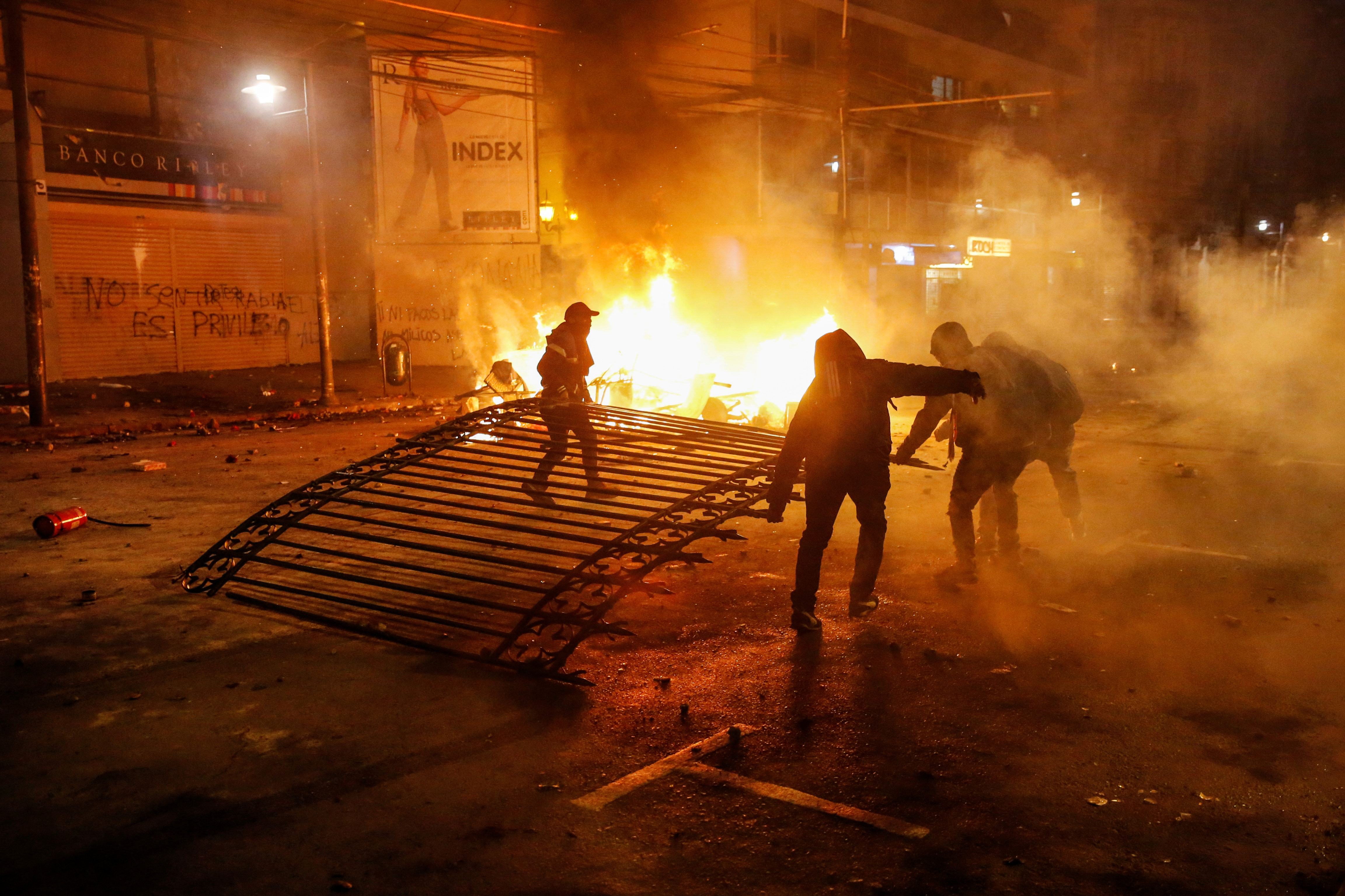 Manifestantes se llevan la puerta de hierro en la entrada de El Mercurio, el periódico más antiguo de Chile.