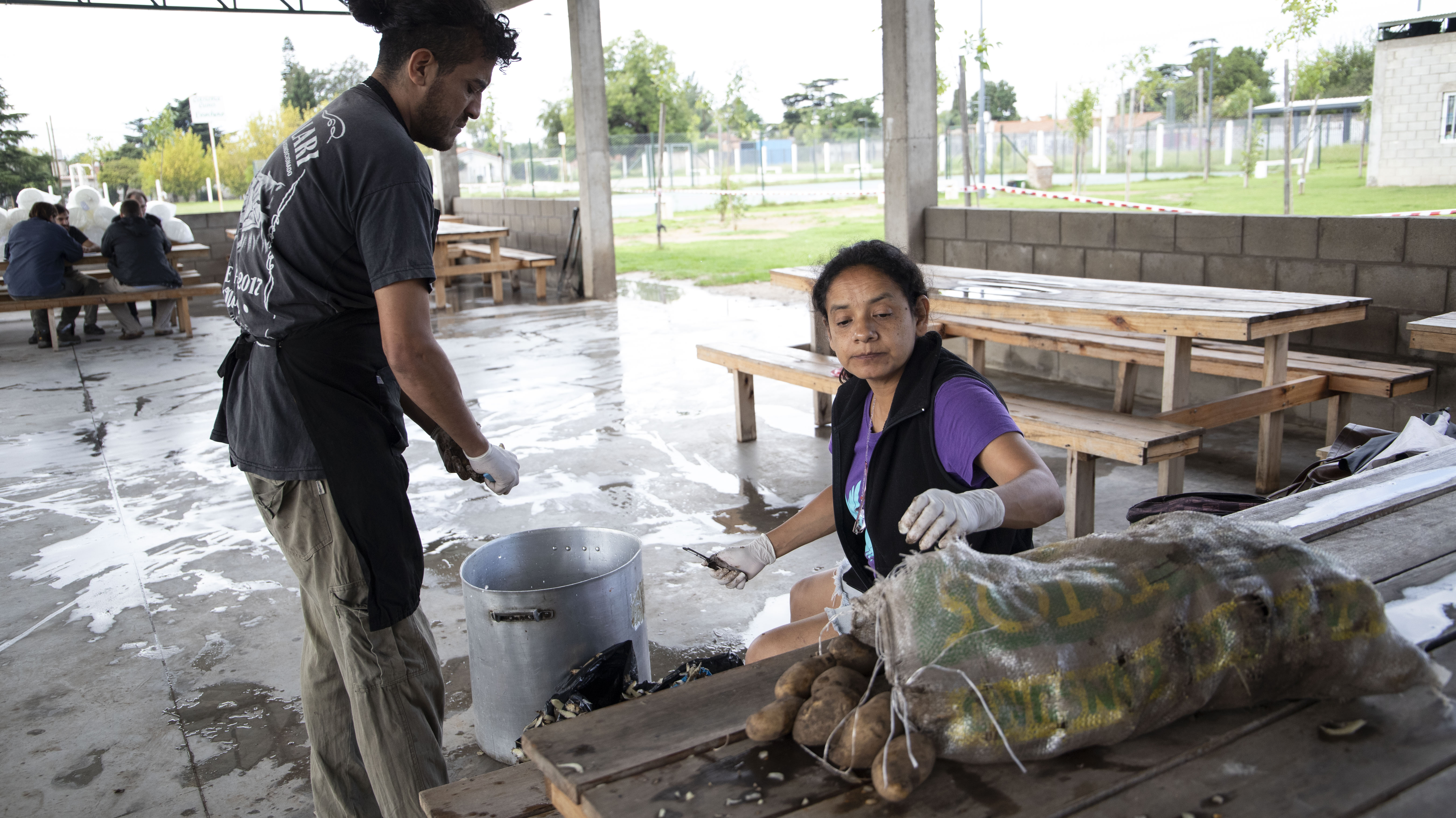 Colaboradores trabajan pelando papas en el medio del campamento militar