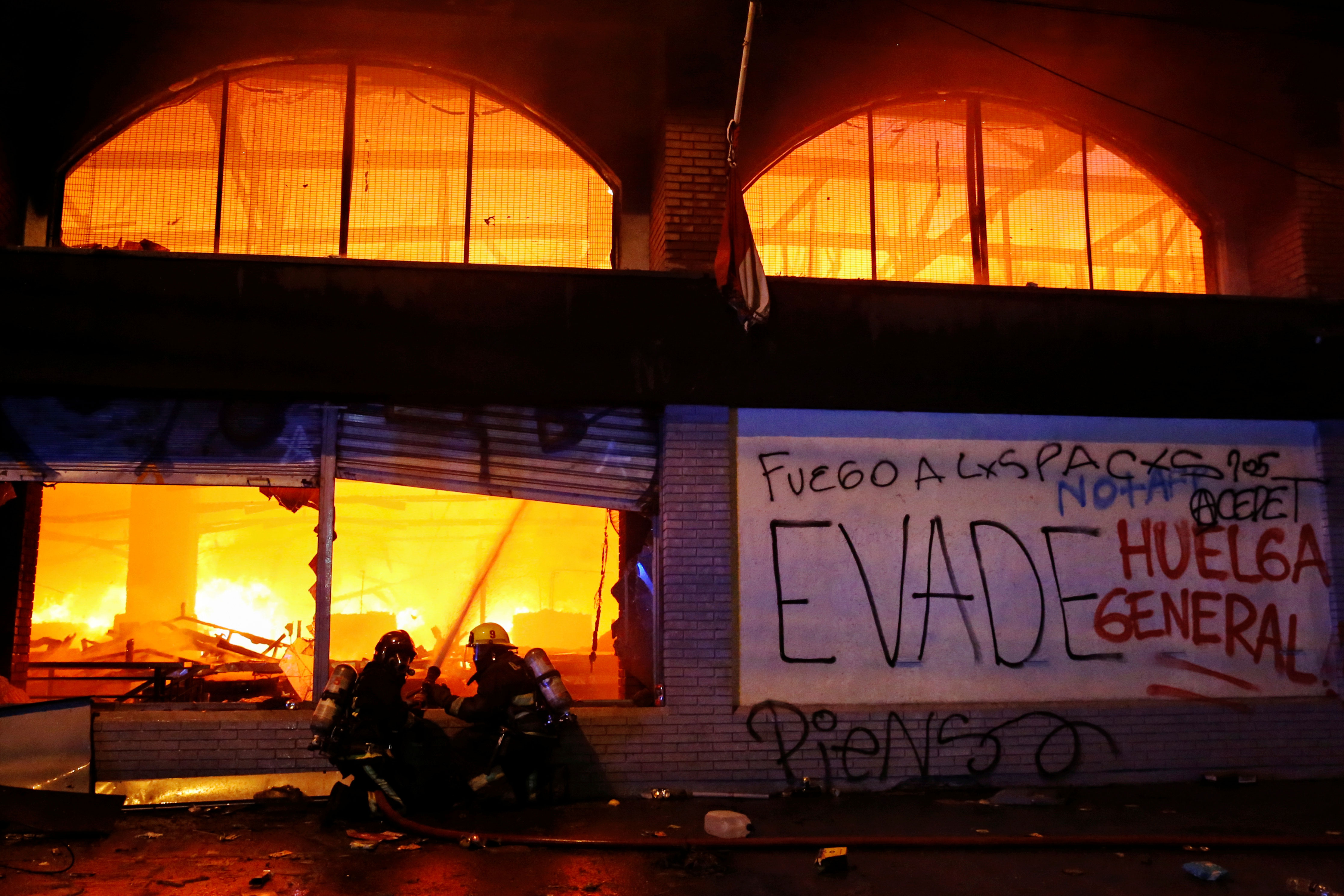 Bomberos combatiendo fuego dentro de una tienda en Santiago, Chile.