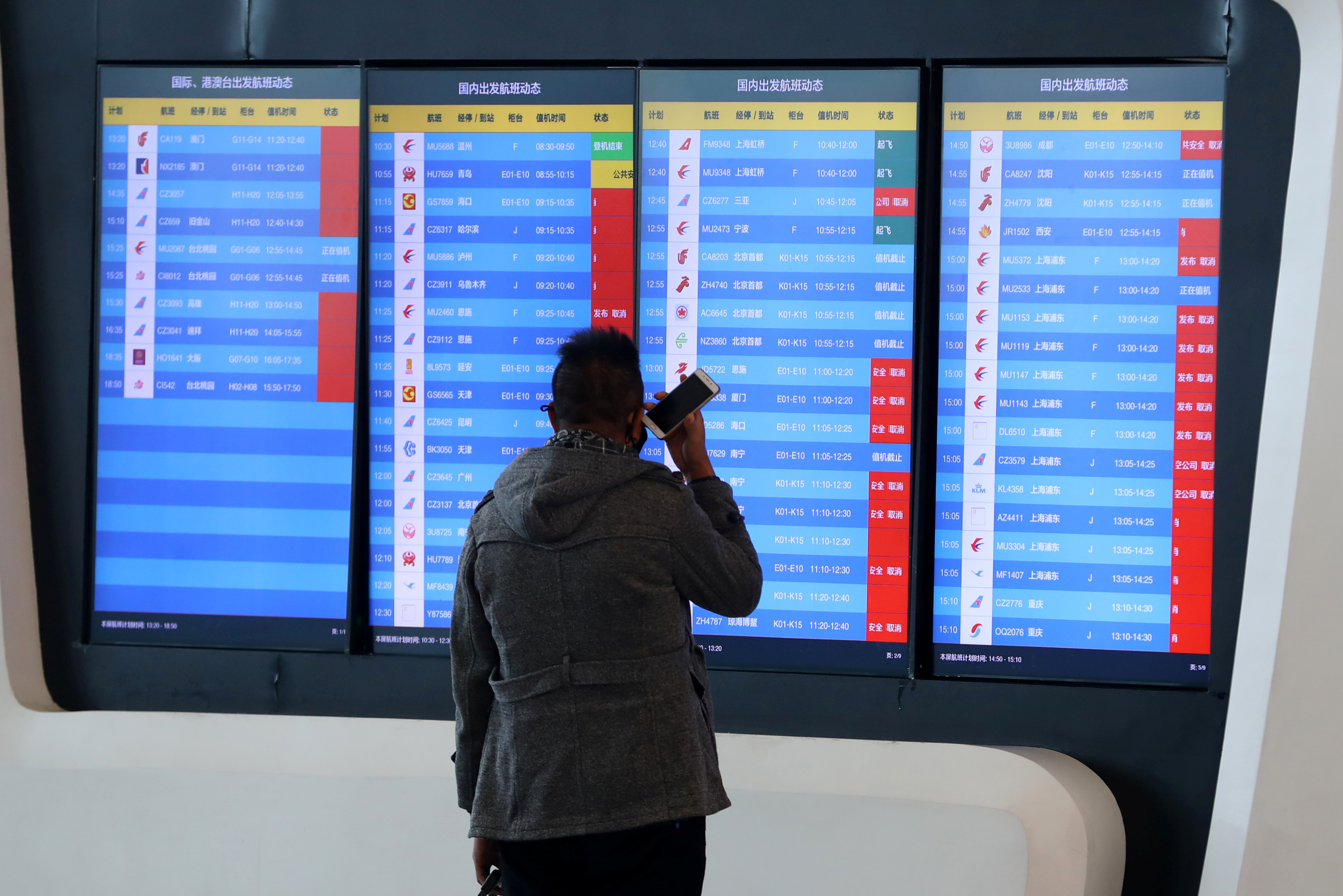 Un hombre observa la pantalla de la terminal aérea de Wuhan que señala que todos los vuelos desde y hacia la ciudad fueron cancelados o desviados (Reuters)