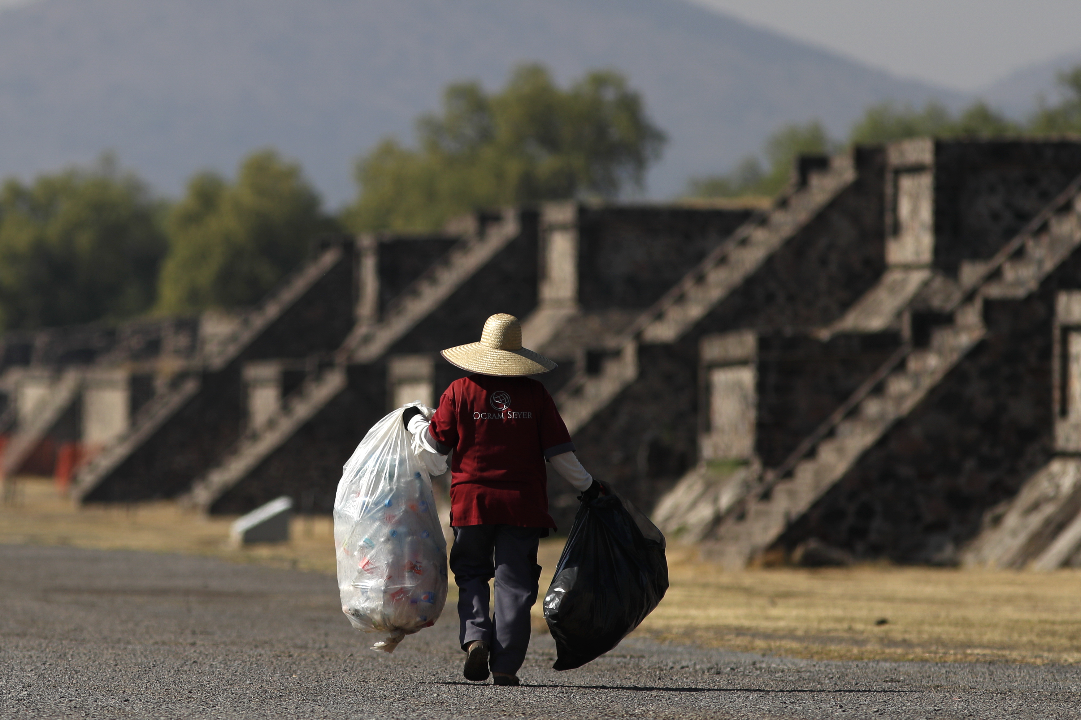 Un miembro del personal de limpieza camina por la Avenida de los Muertos mientras recoge basura en el sitio arqueológico de Teotihuacán en México, el jueves 19 de marzo de 2020.