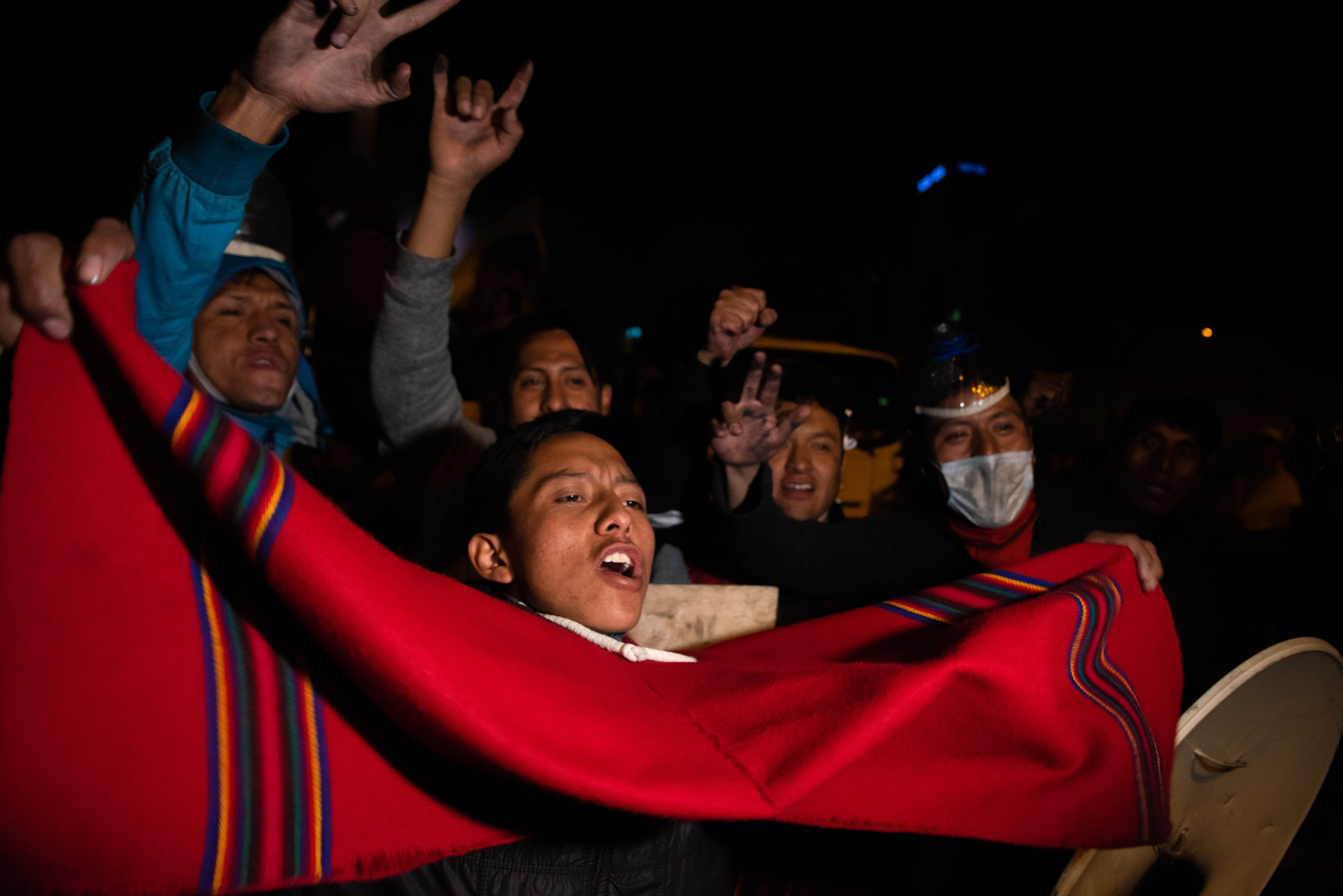 Un joven celebra en las calles de Quito con un poncho rojo.