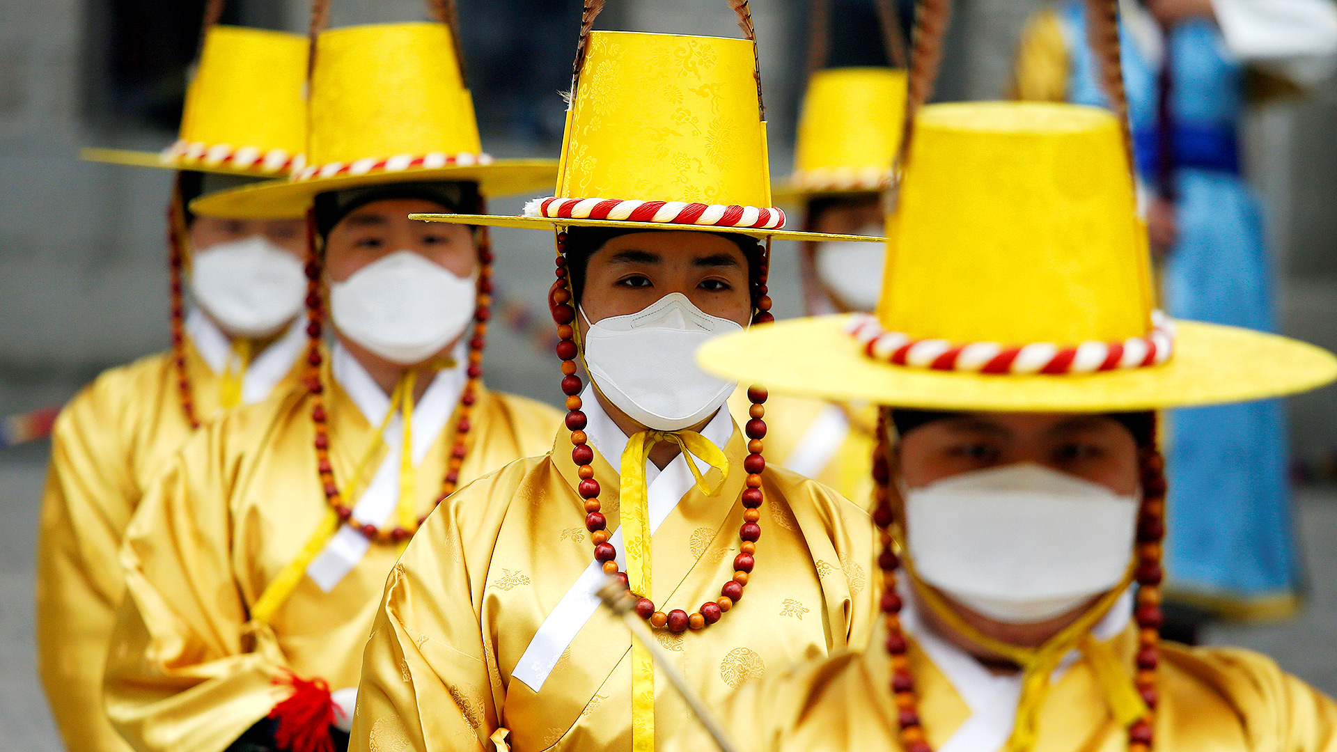 Trabajadores en trajes tradicionales coreanos usan máscaras protectoras para evitar contraer el coronavirus durante una recreación de la Ceremonia de Cambio de la Guardia Real frente al Palacio Deoksu en Seúl, Corea del Sur (REUTERS / Heo Ran)