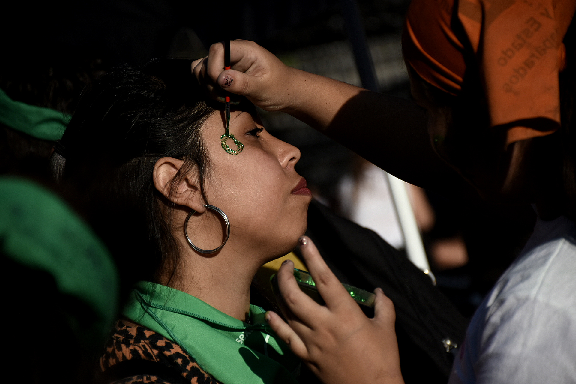 Una joven se pinta la cara con el color verde, símbolo del aborto legal