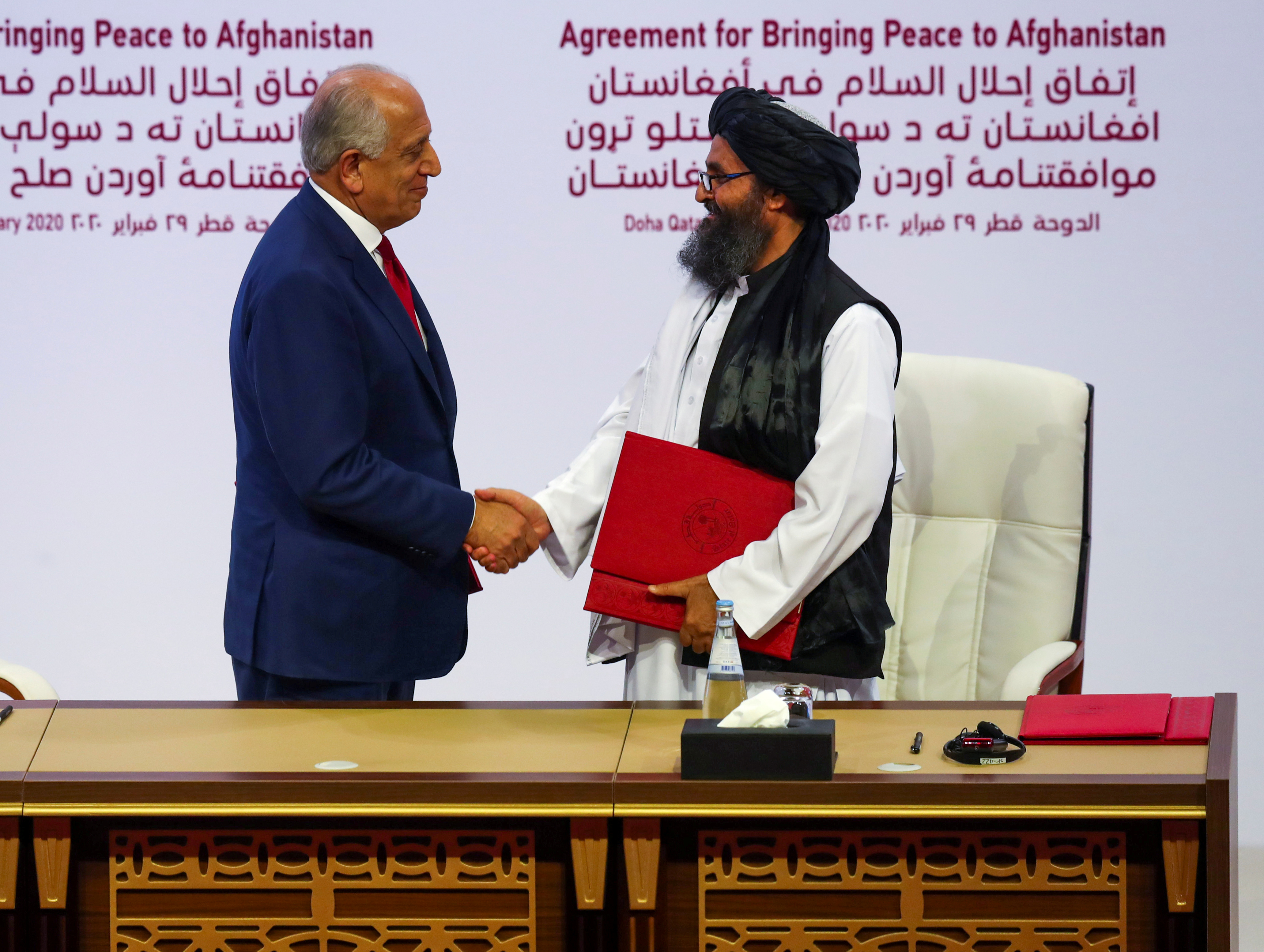 Mullah Abdul Ghani Baradar, líder talibán, y Zalmay Khalilzad, negociador de EEUU, en la firma del pacto en Doha el pasado sábado (REUTERS/Ibraheem al Omari)