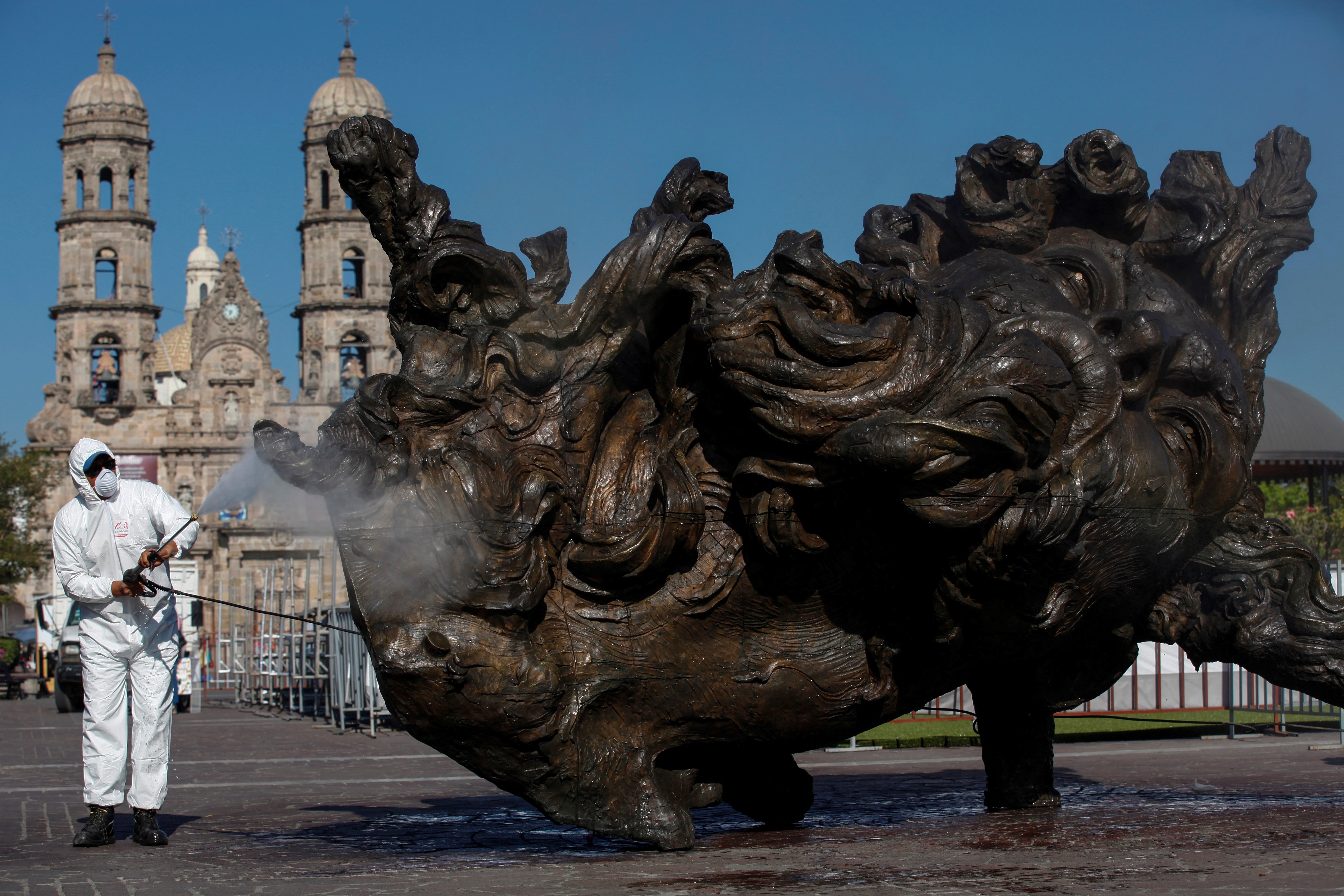Un hombre lava y desinfecta una escultura el 20 de marzo de 2020 en el municipio de Zapopan, estado de Jalisco (México). (Foto: EFE/Francisco Guasco)