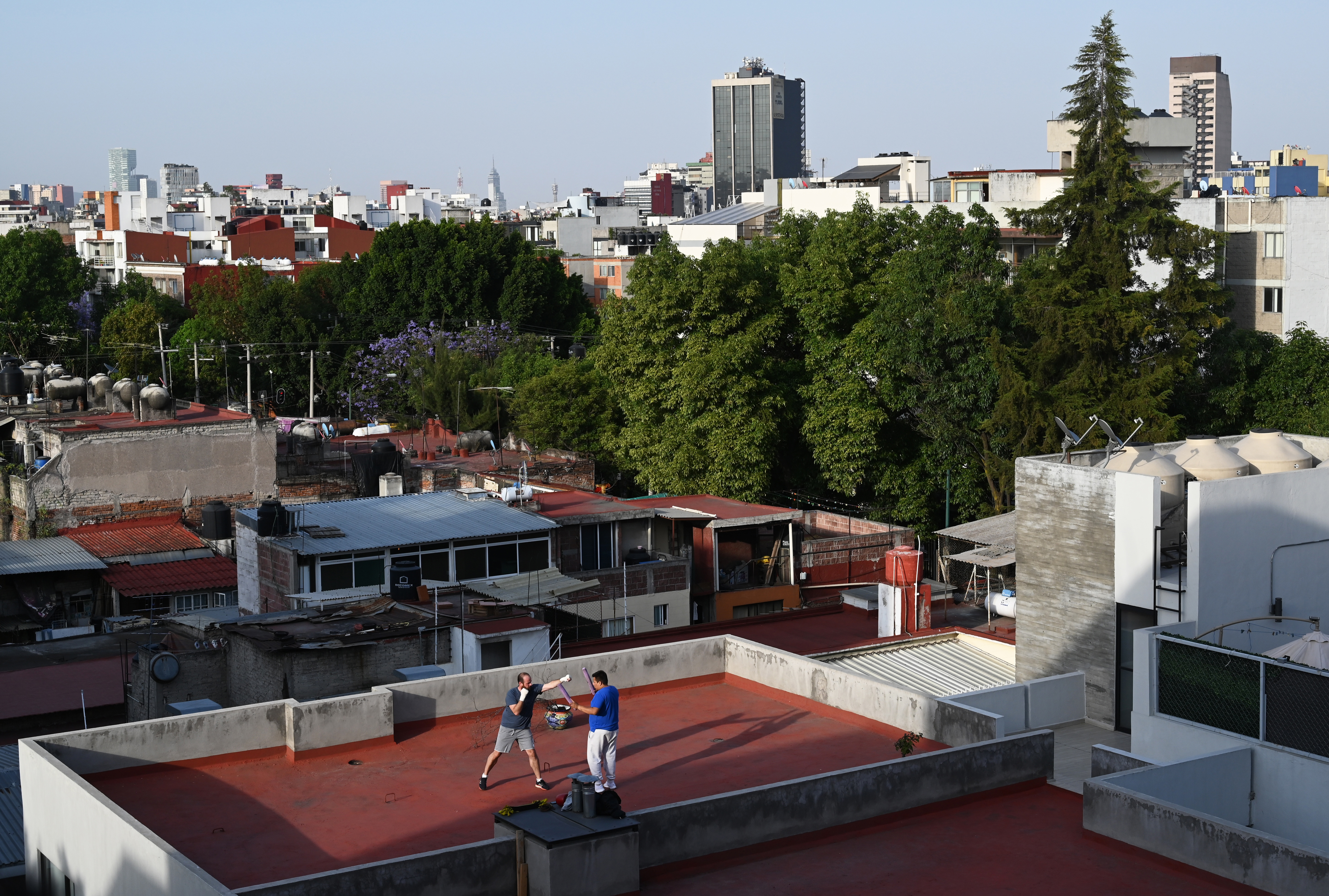 Un hombre practica boxeo con su entrenador en la azotea de un edificio en la Ciudad de México el 31 de marzo de 2020 durante la nueva pandemia de coronavirus COVID-19.