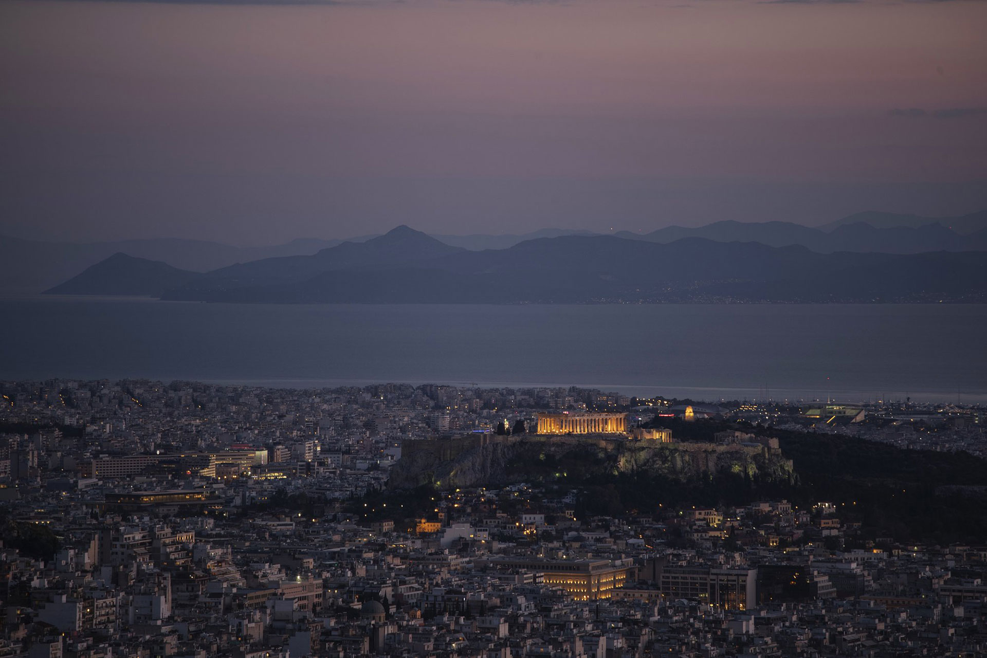 La Acrópolis de Atenas, Grecia, iluminada mientras la isla de Aegina se alza en el fondo y detrás de ella las distantes costas de la península del Peloponeso, el viernes 24 de abril (Foto AP / Petros Giannakouris)