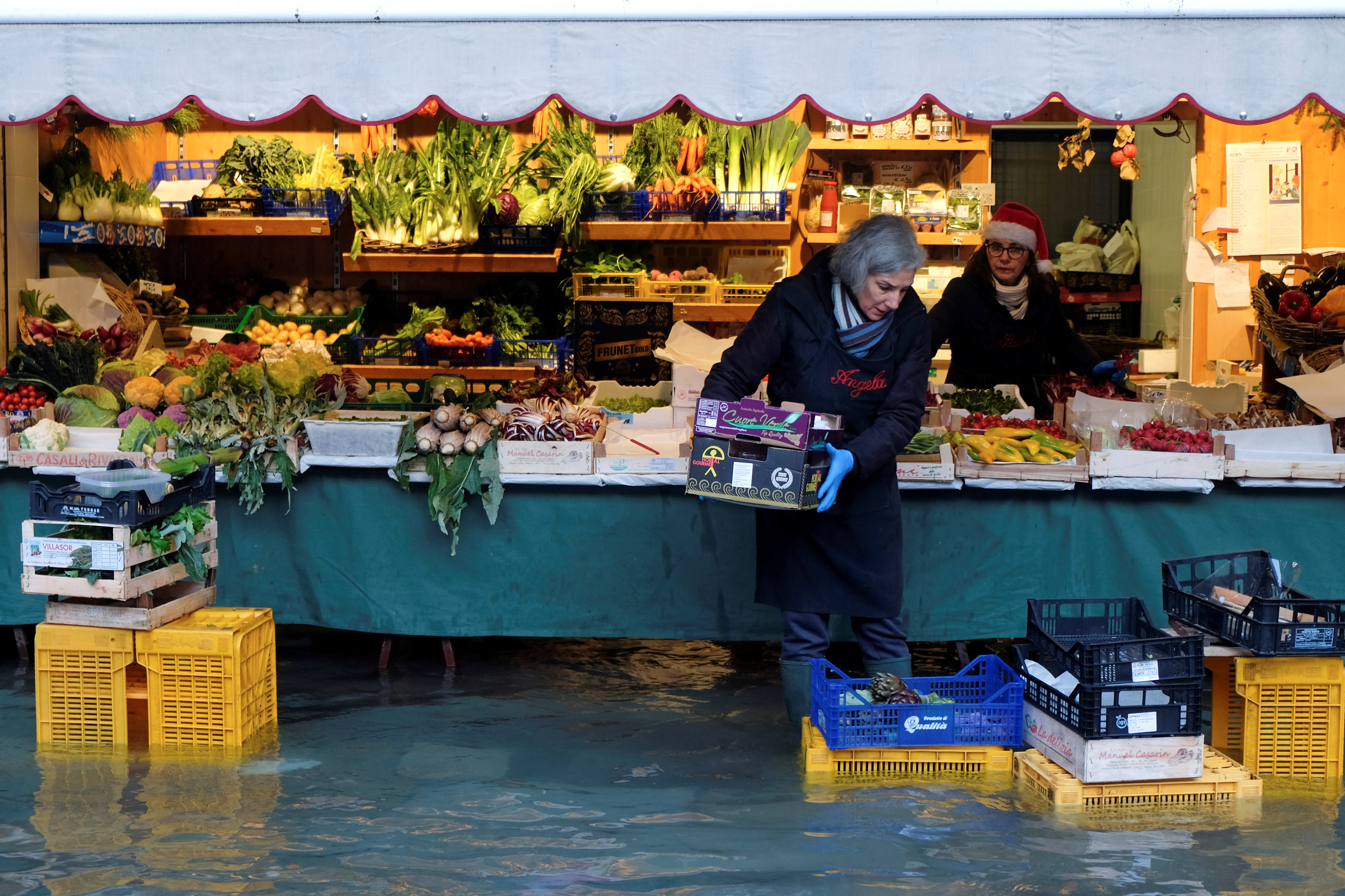 Una mujer lleva una caja delante de su puesto de verduras en Venecia (REUTERS/Manuel Silvestri)