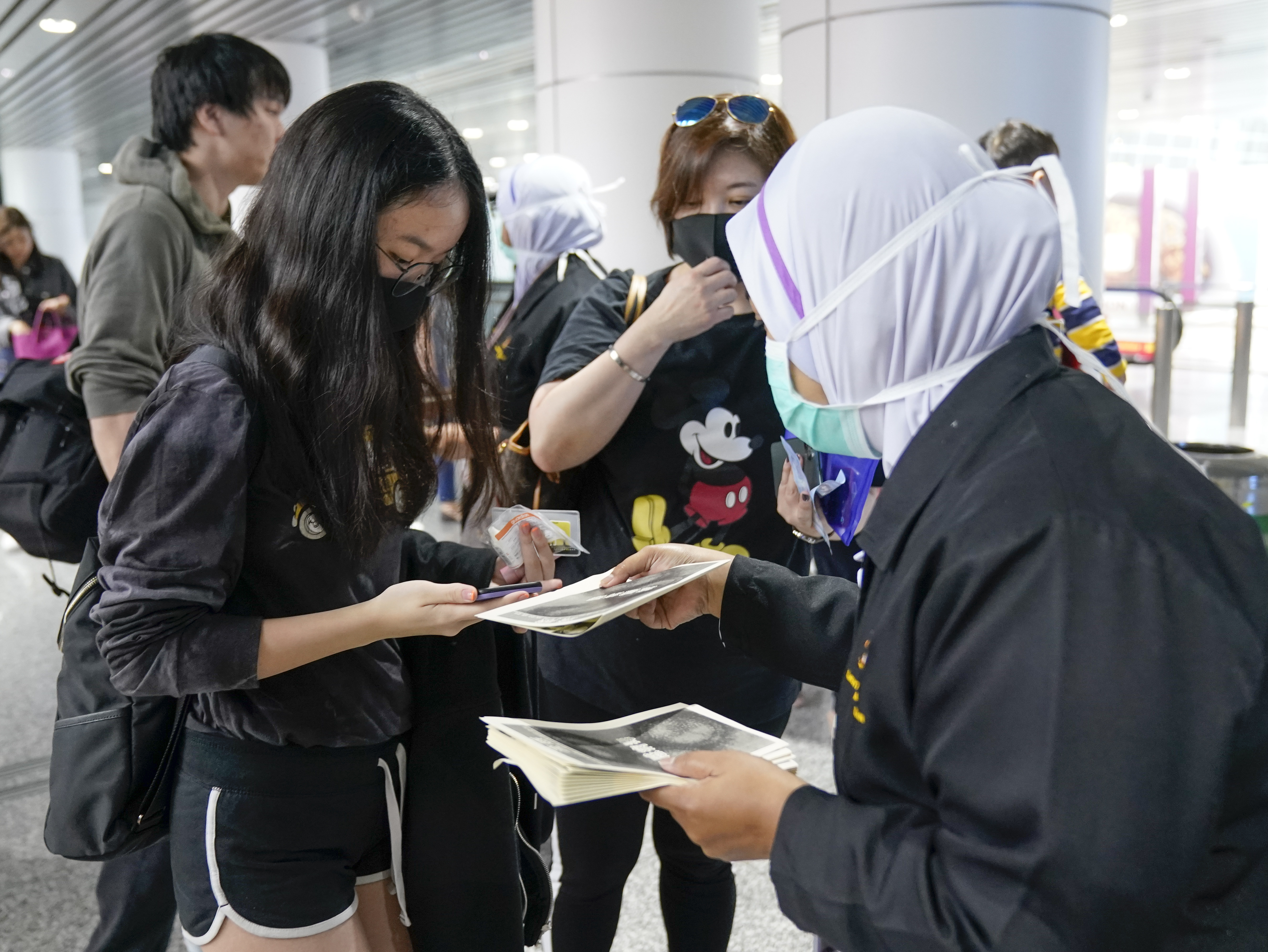Los funcionarios de salud entregan información sobre el coronavirus actual en el aeropuerto internacional de Kuala Lumpur en Sepang, Malasia, el martes 21 de enero de 2020. Países tanto en Asia-Pacífico como en otros lugares han iniciado controles de temperatura corporal en aeropuertos, estaciones de ferrocarril y a lo largo de carreteras en espera atrapar a quienes corren el riesgo de portar un nuevo coronavirus que ha enfermado a más de 200 personas en China. (Foto AP / Vincent Thian)