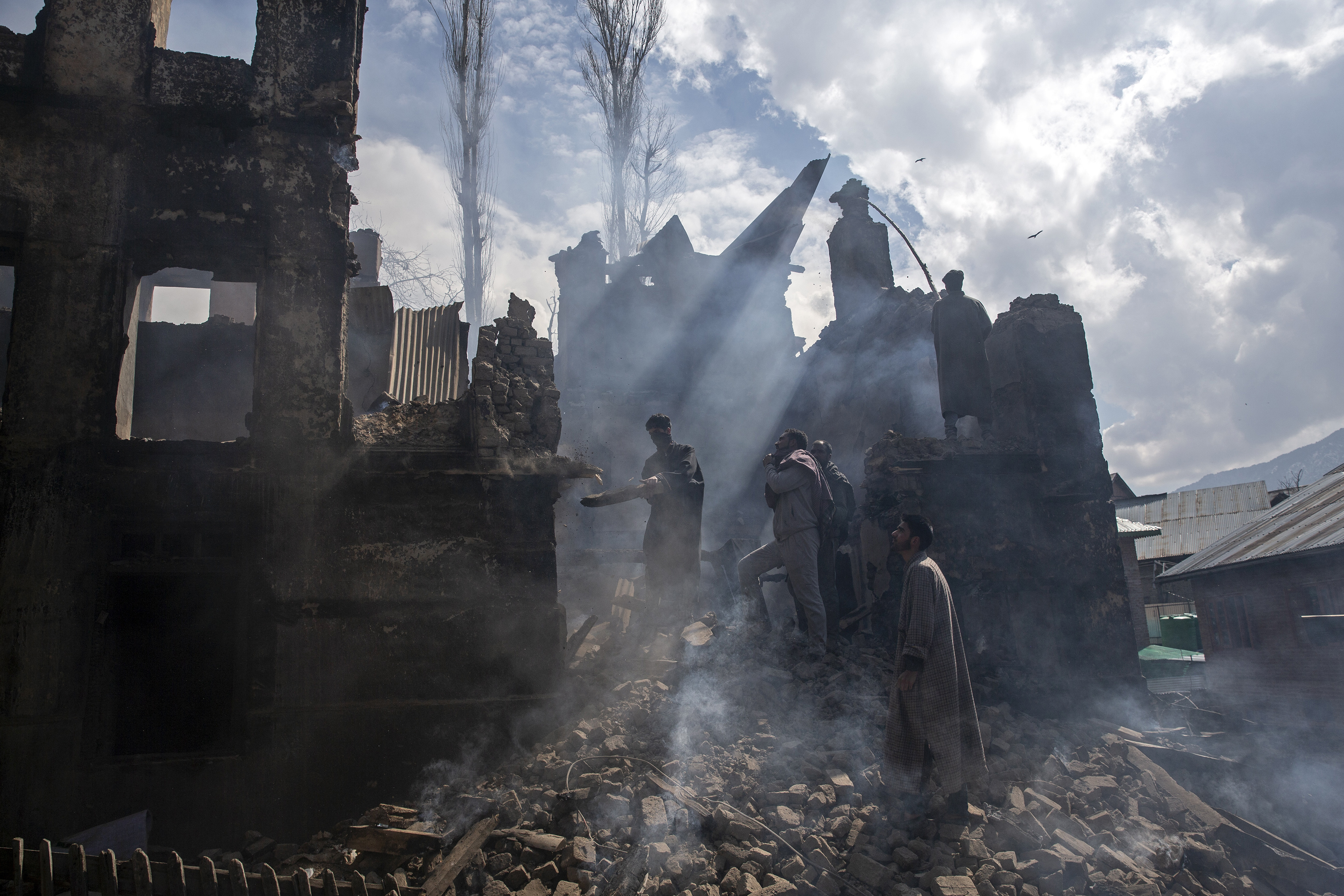 Los hombres de Cachemira desmantelan una parte de una casa destruida en un tiroteo en la aldea de Tral, al sur de Srinagar, Cachemira (Foto AP / Dar Yasin)