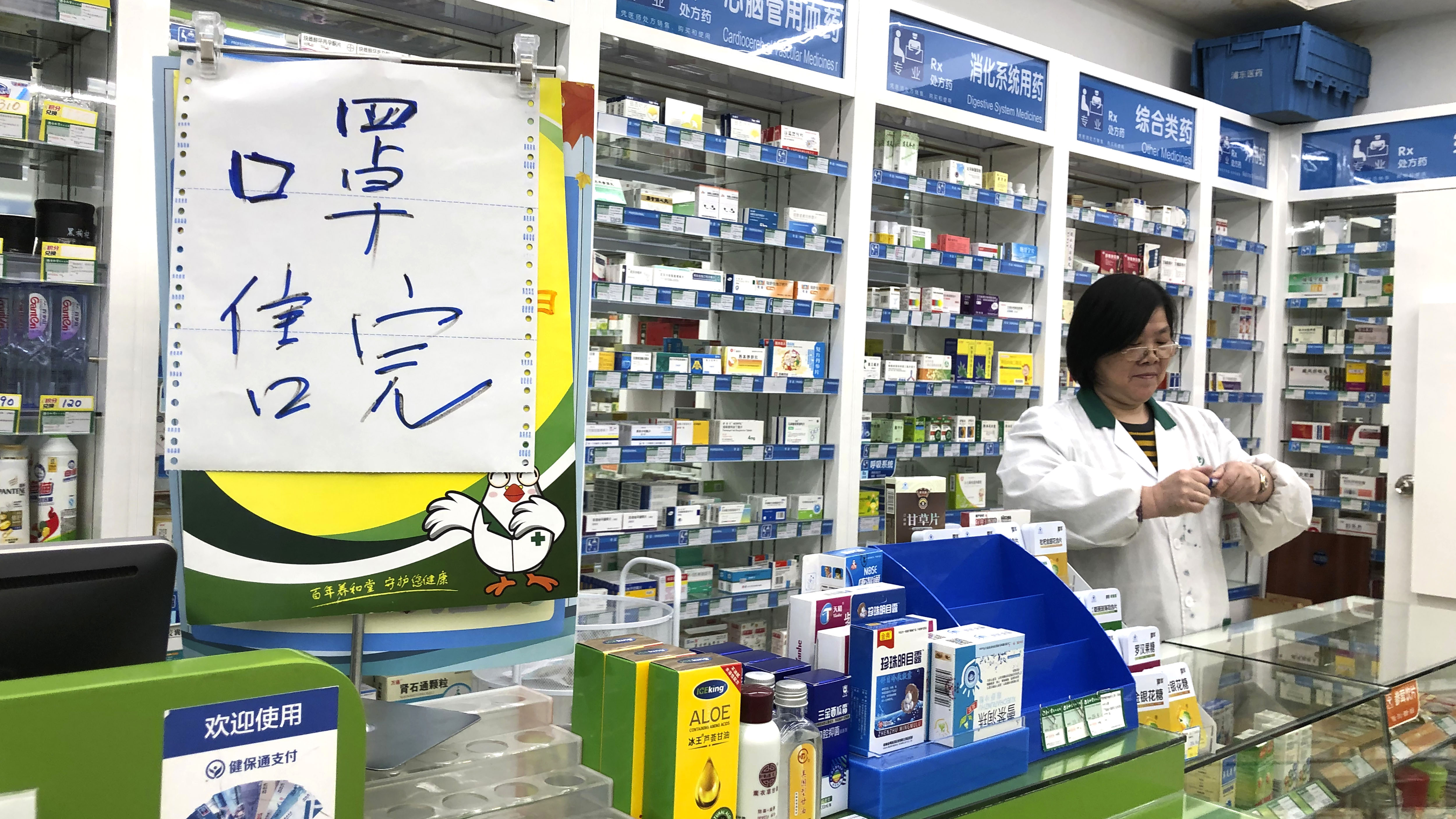 El farmacéutico Liu Zhuzhen se encuentra cerca de un letrero que dice