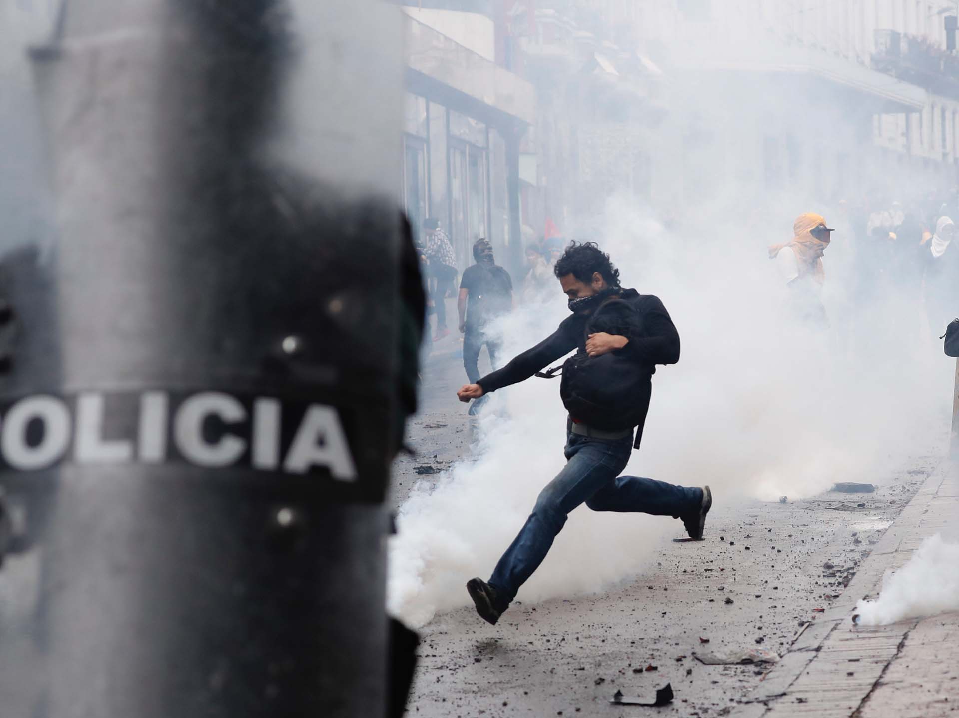 Un joven patea una bomba lacrimógena arrojada por la policía (AP Photo/Dolores Ochoa)