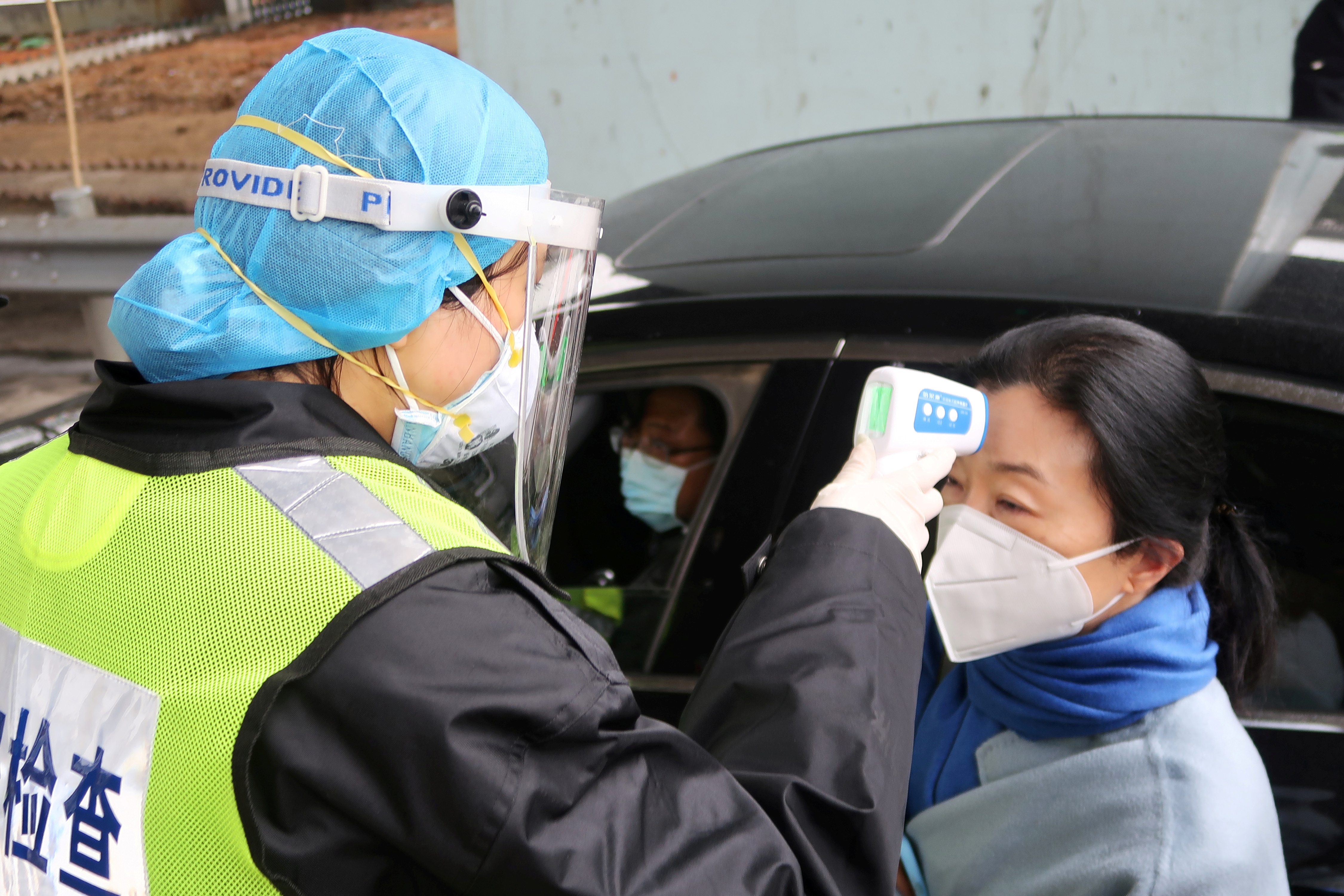 Un oficial de seguridad con una máscara protectora comprueba la temperatura de un pasajero tras el brote de un nuevo coronavirus, en una estación de peaje de una autopista en la víspera de las celebraciones del Año Nuevo Lunar chino, en Xianning, una ciudad fronteriza con Wuhan al norte, en la provincia de Hubei, China, el 24 de enero de 2020. (REUTERS)