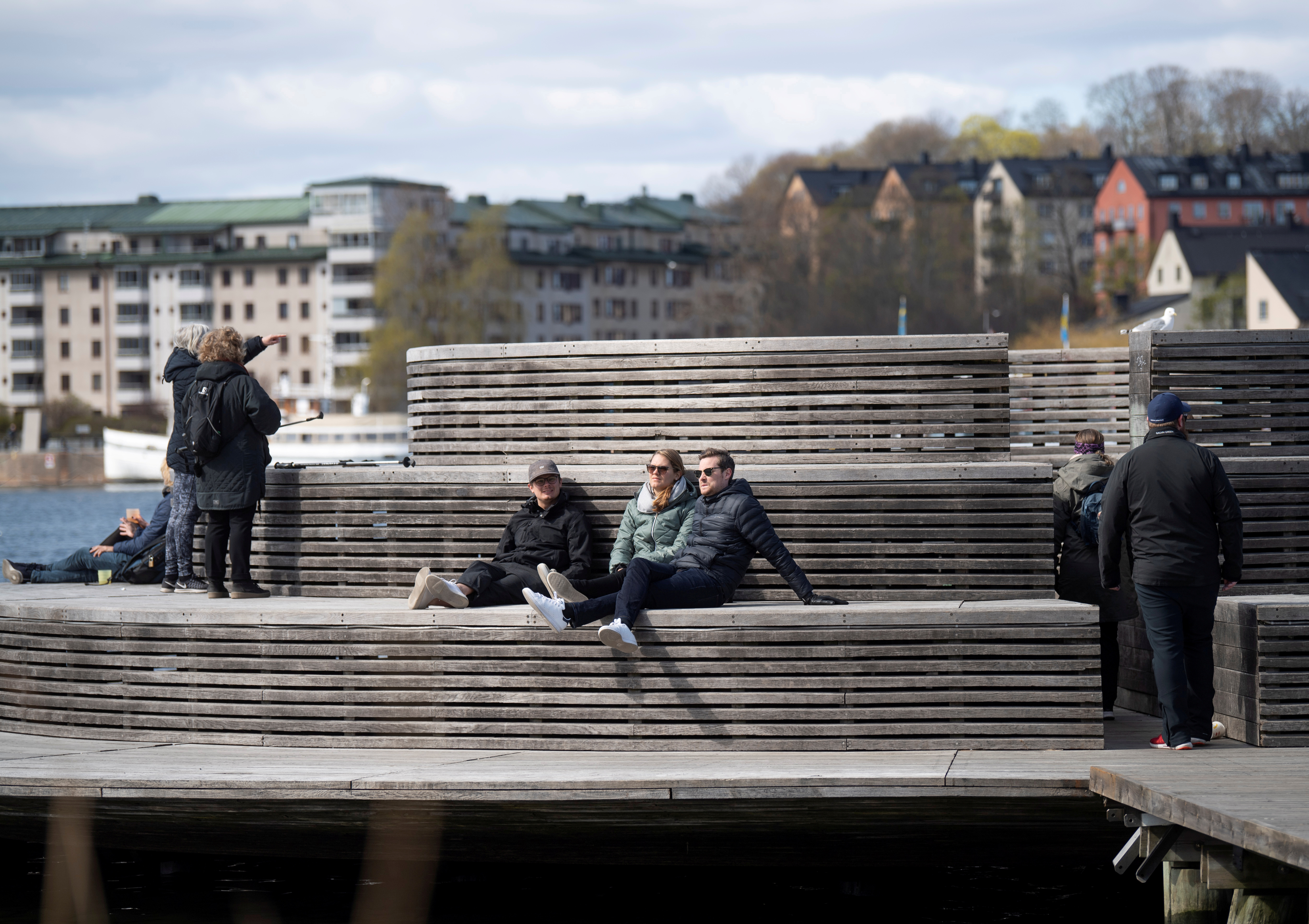 Personas disfrutan del sol primaveral en el barrio Hammarby Sjostad de Estocolmo (Fredrik Sandberg /TT News Agency/via REUTERS)