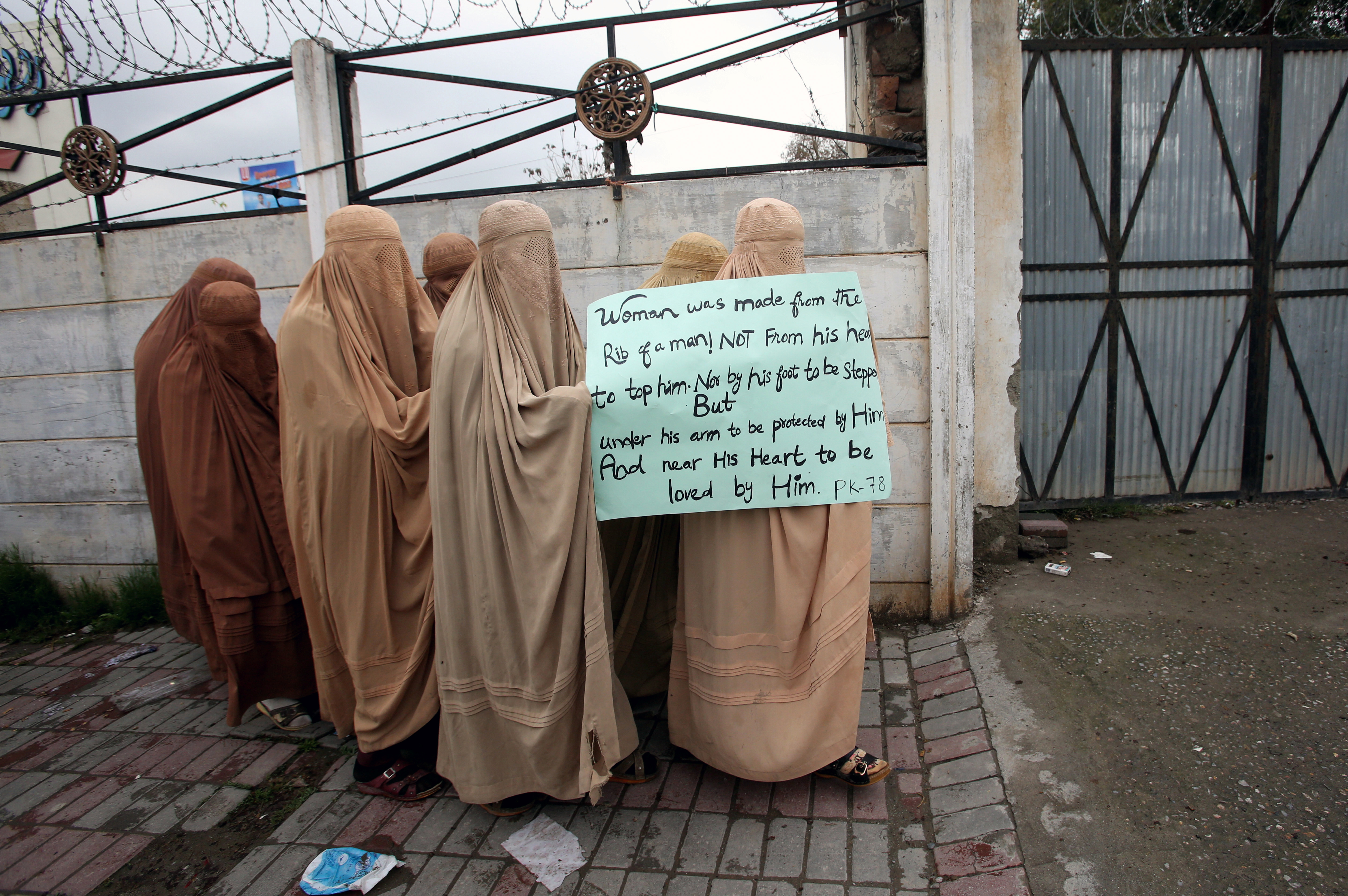 Mujeres simpatizantes del partido político y religioso Jamiat Ulema-e-Islam-Fazal (JUI-F) vestidas con burkas, sostienen una pancarta para asistir a una Marcha de las Mujeres, en Peshawar, Pakistán (REUTERS / Khurram Parvez)