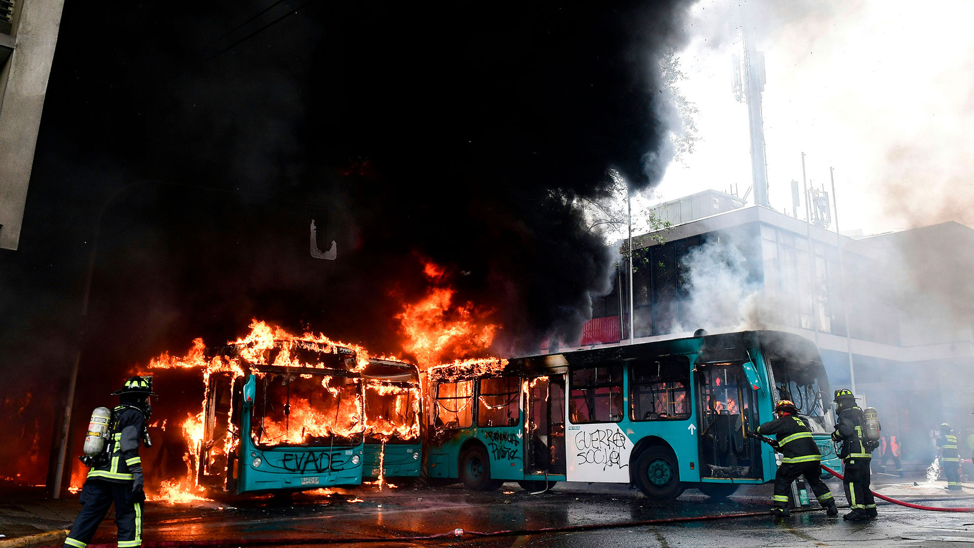 Los bomberos santiaguinos combaten las llamas dentro de los autobuses públicos.
