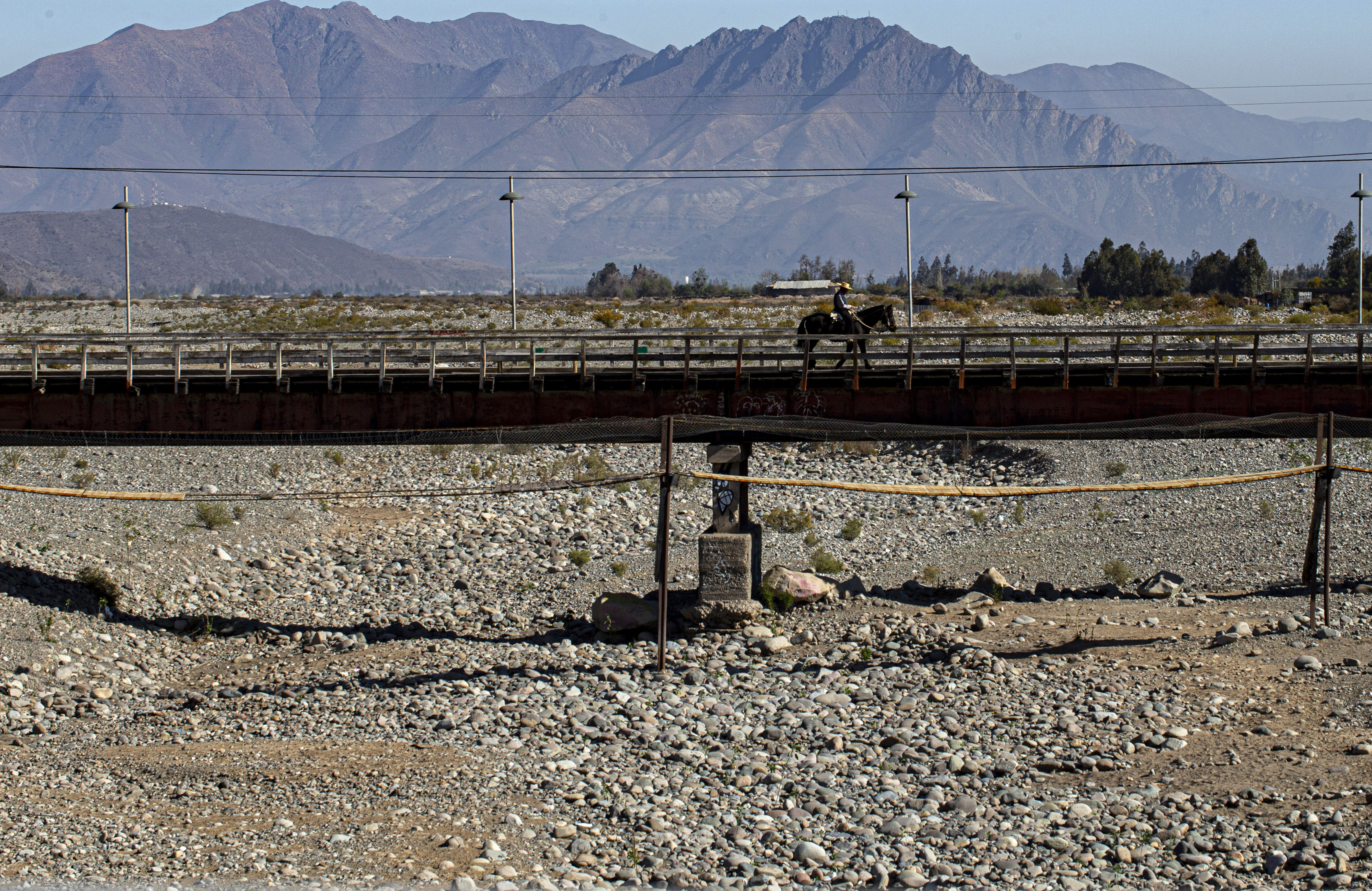 Un jinete cruza un puente sobre el lecho de un río que quedó seco por la peor sequía de Chile en más de medio siglo, en Putaendo