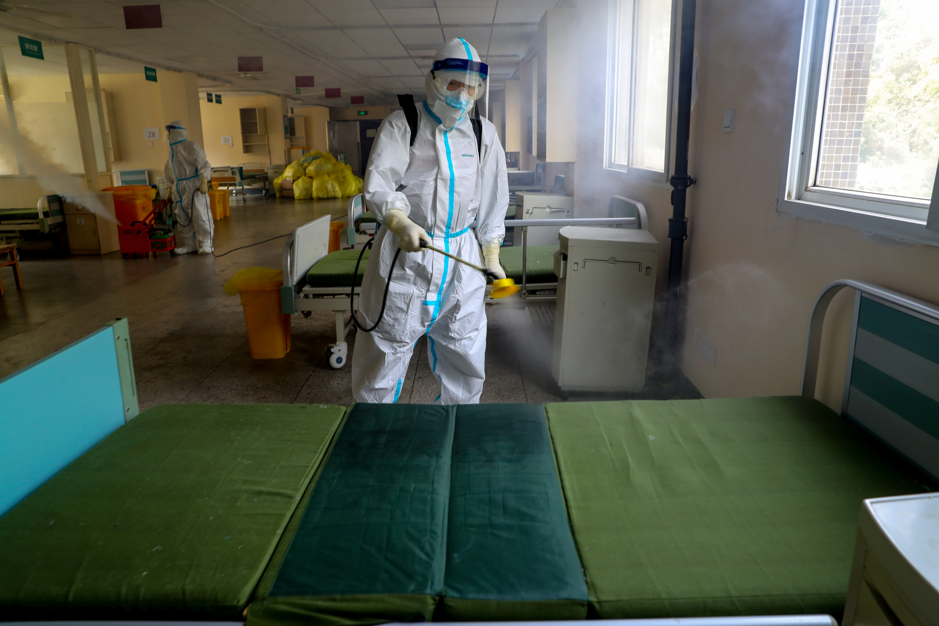 Un trabajador con traje de protección desinfecta el Hospital N°. 7 de Wuhan