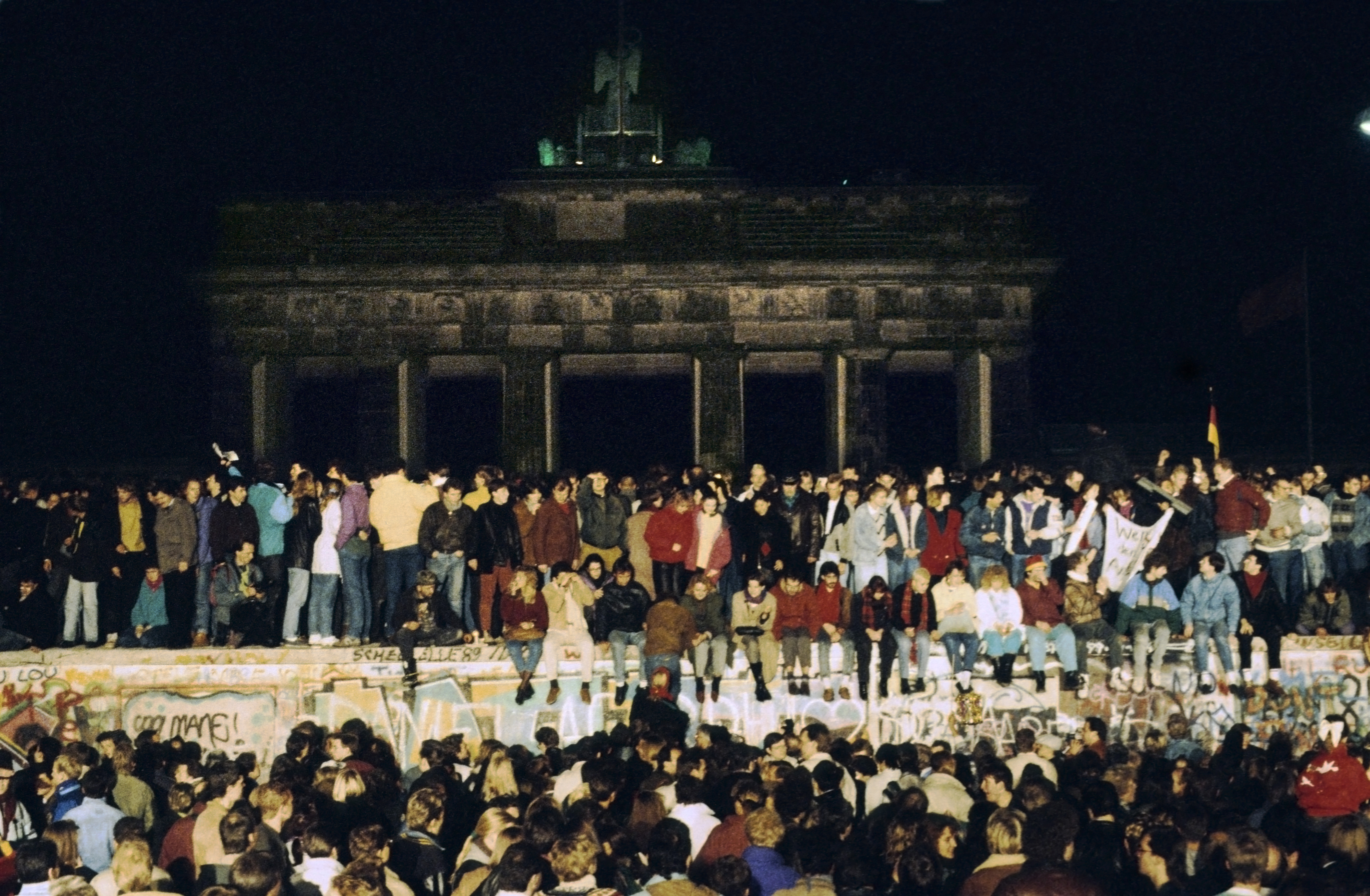 Miles de jóvenes se trepan al muro en la noche del 9 de noviembre de 1989. Los guardias no están a la vista. La pared todavía está de pie, pero el muro ha caído.