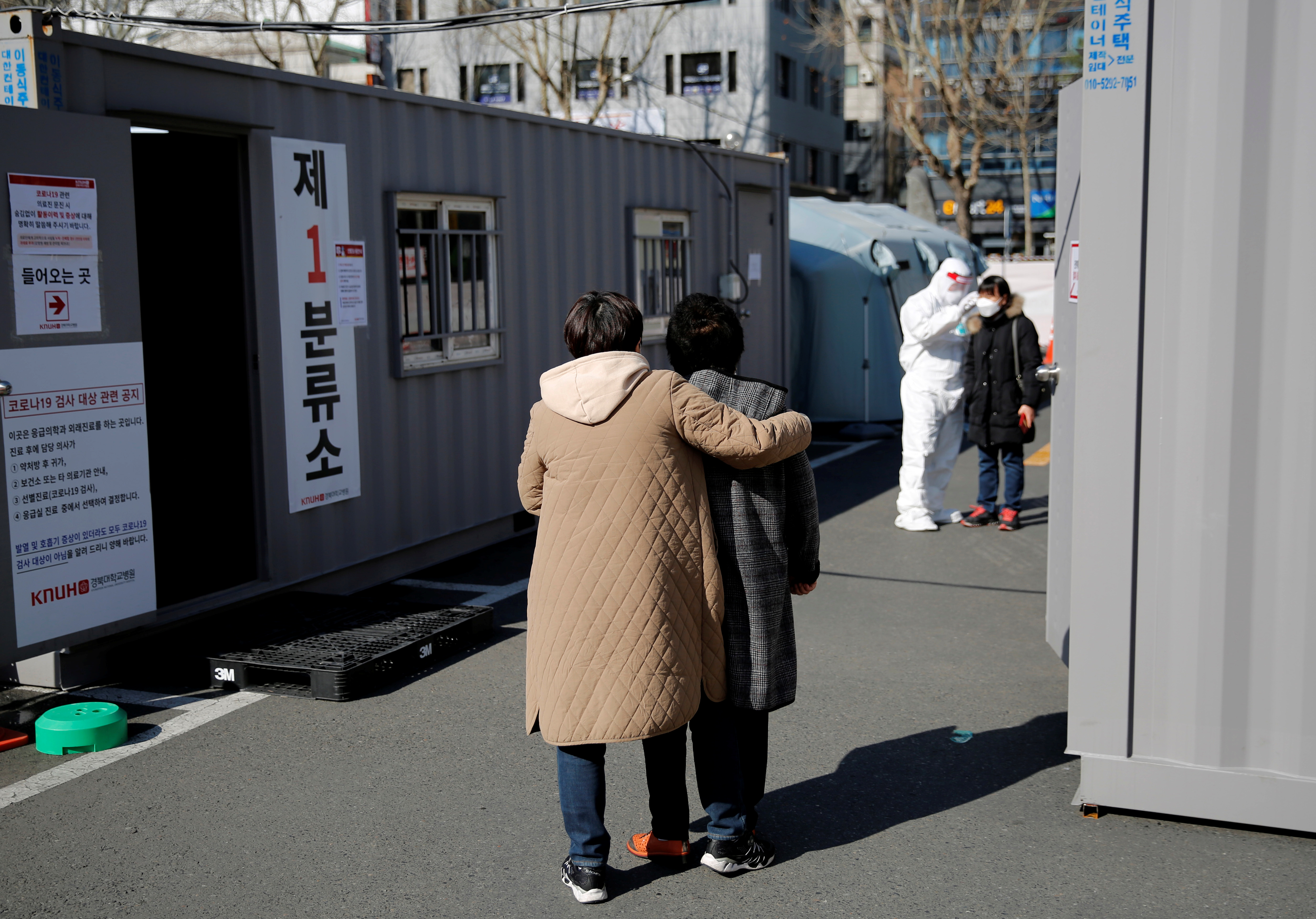 Una mujer con su hija espera su turno para que le tomen la temperatura en el puesto de control de la primera etapa para comprobar la enfermedad coronavirus (COVID-19) en el Hospital Universitario Nacional de Kyungpook en Daegu, el 6 de marzo de 2020 (Reuters/ Kim Kyung-Hoon)