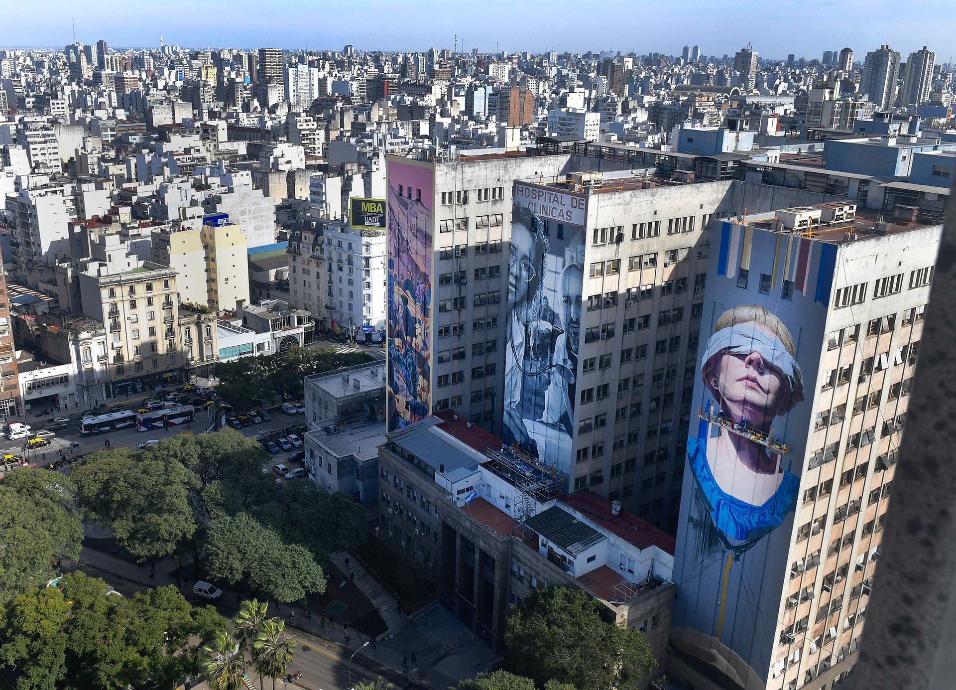 Los tres murales que representan el Atentado a la AMIA sobre los pilares del Hospital de Clínicas, donde se recibieron a los afectados de la explosión. Las obras callejeras pintadas por los artistas Mariano Antedoménico, Martín Ron y Mariela Ajras fueron presentadas en el 25° aniversario del atentado. La imagen del fotógrafo vuela desde los techos de la Facultad de Medicina