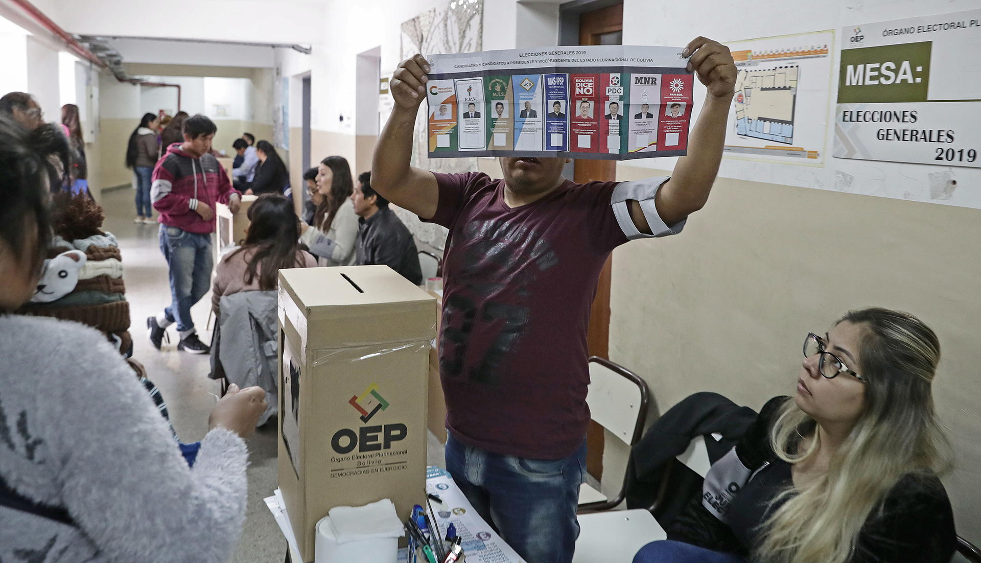 Una de las autoridades de mesa muestra la boleta a los ciudadanos bolivianos residentes en Buenos Aires que se preparar para emitir su voto