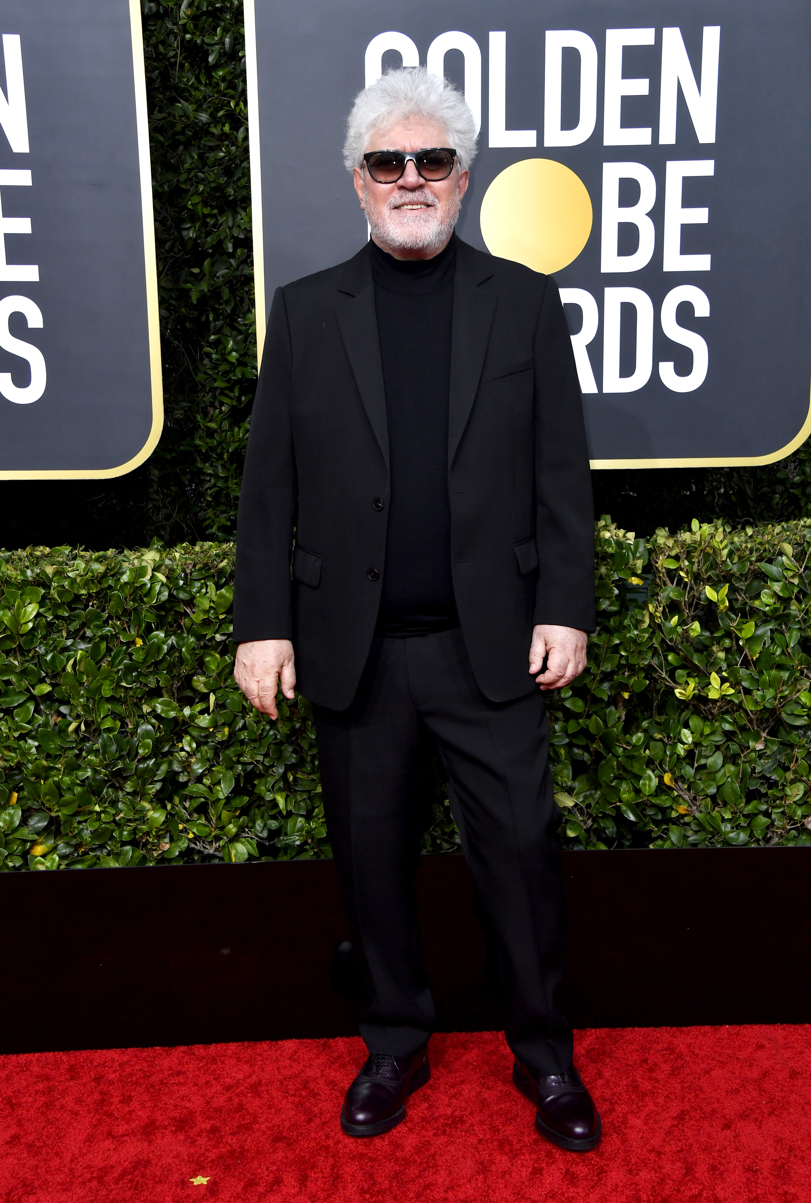 Pedro Almodóvar eligió para la red carpet de los Golden Globe un traje negro pero a diferencia de una camisa optó por una polera negra. Como complemento, llevó sus características gafas negras