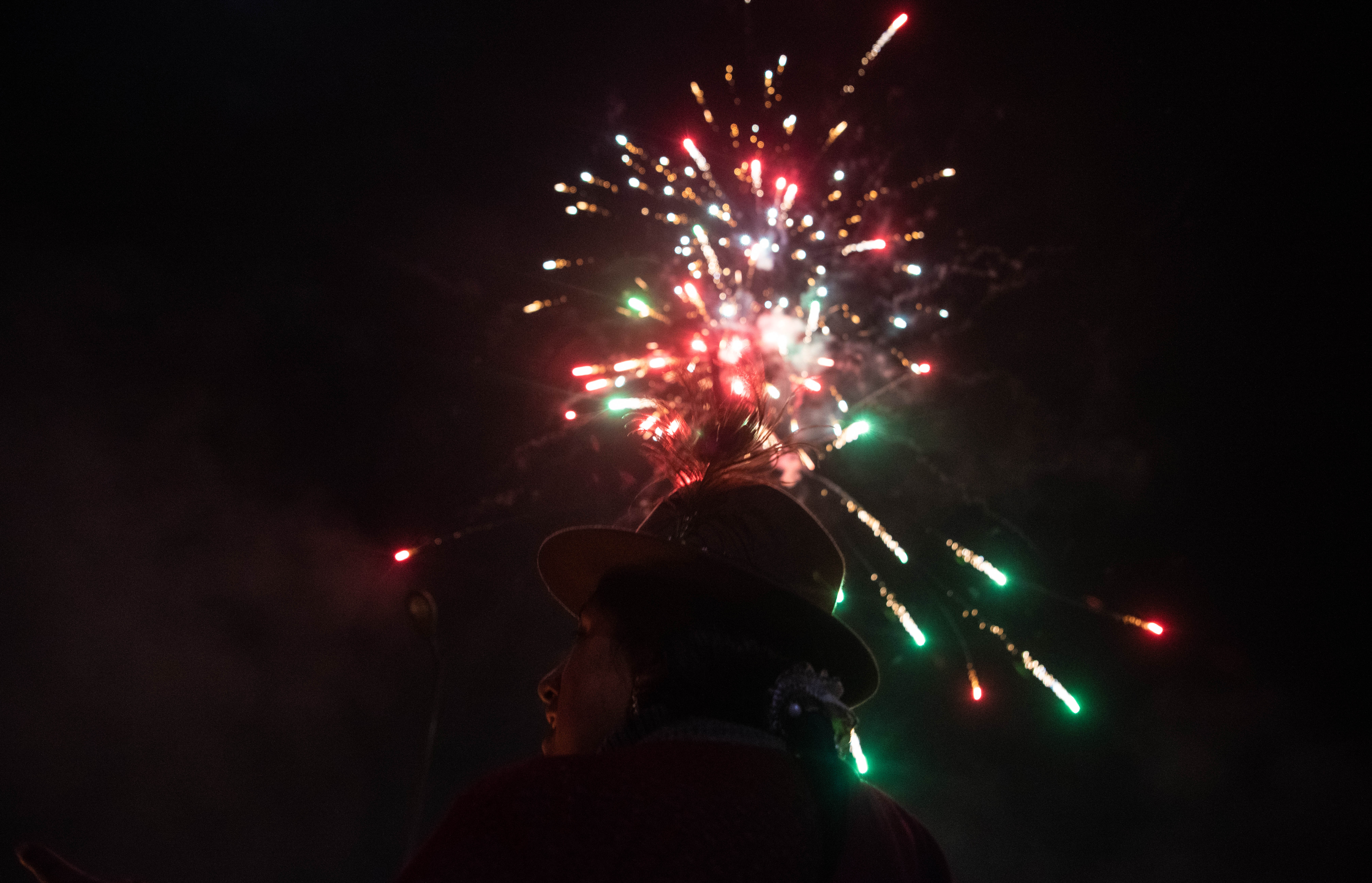 Una mujer con vestimenta tradicional de las comunidades aborígenes de Ecuador presencia los fuegos artificiales de los festejos