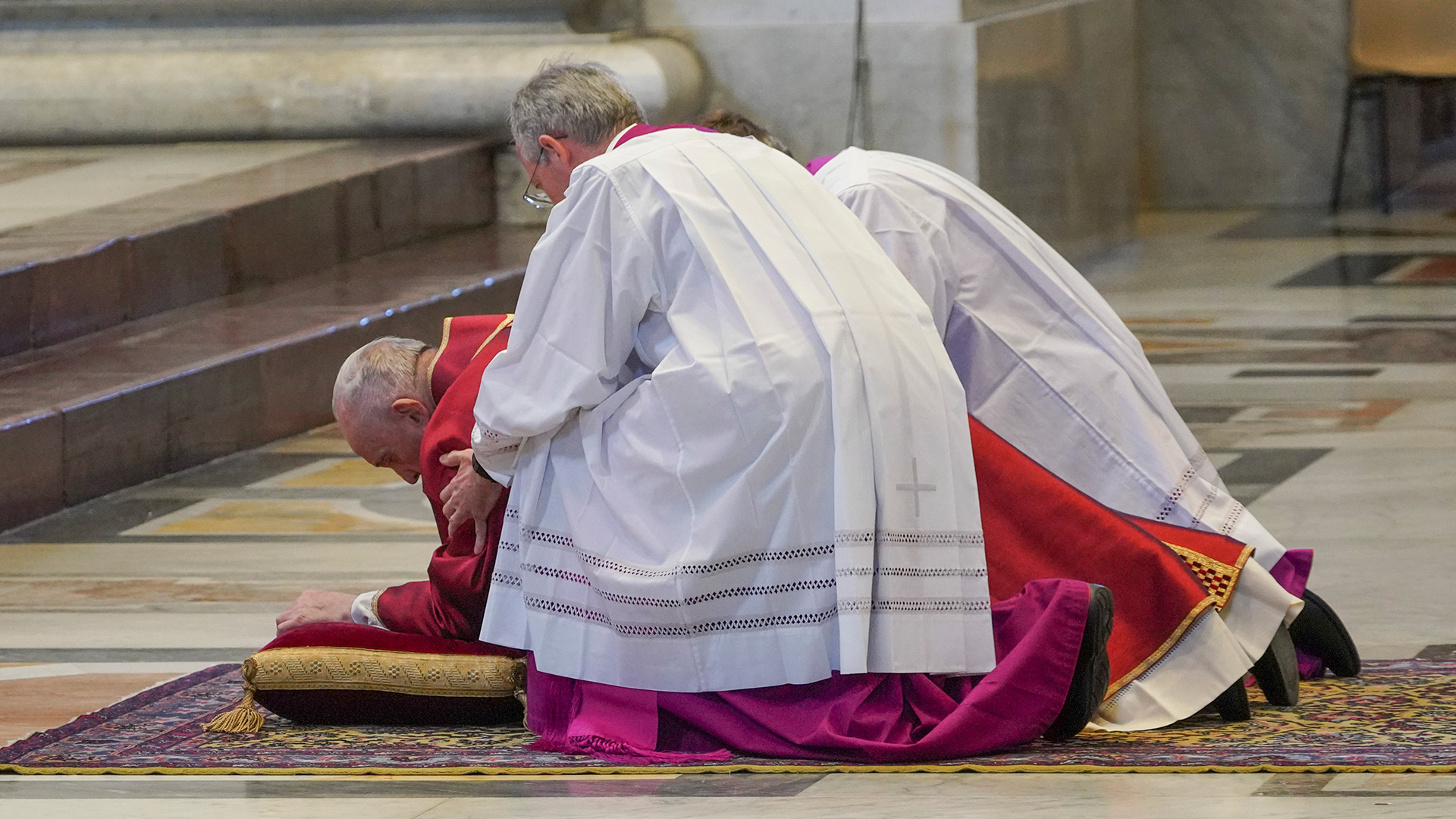 El papa Francisco es asistido para levantarse del suelo después del rezo para celebrar la pasión de Cristo (Photo by Andrew Medichini / POOL / AFP)