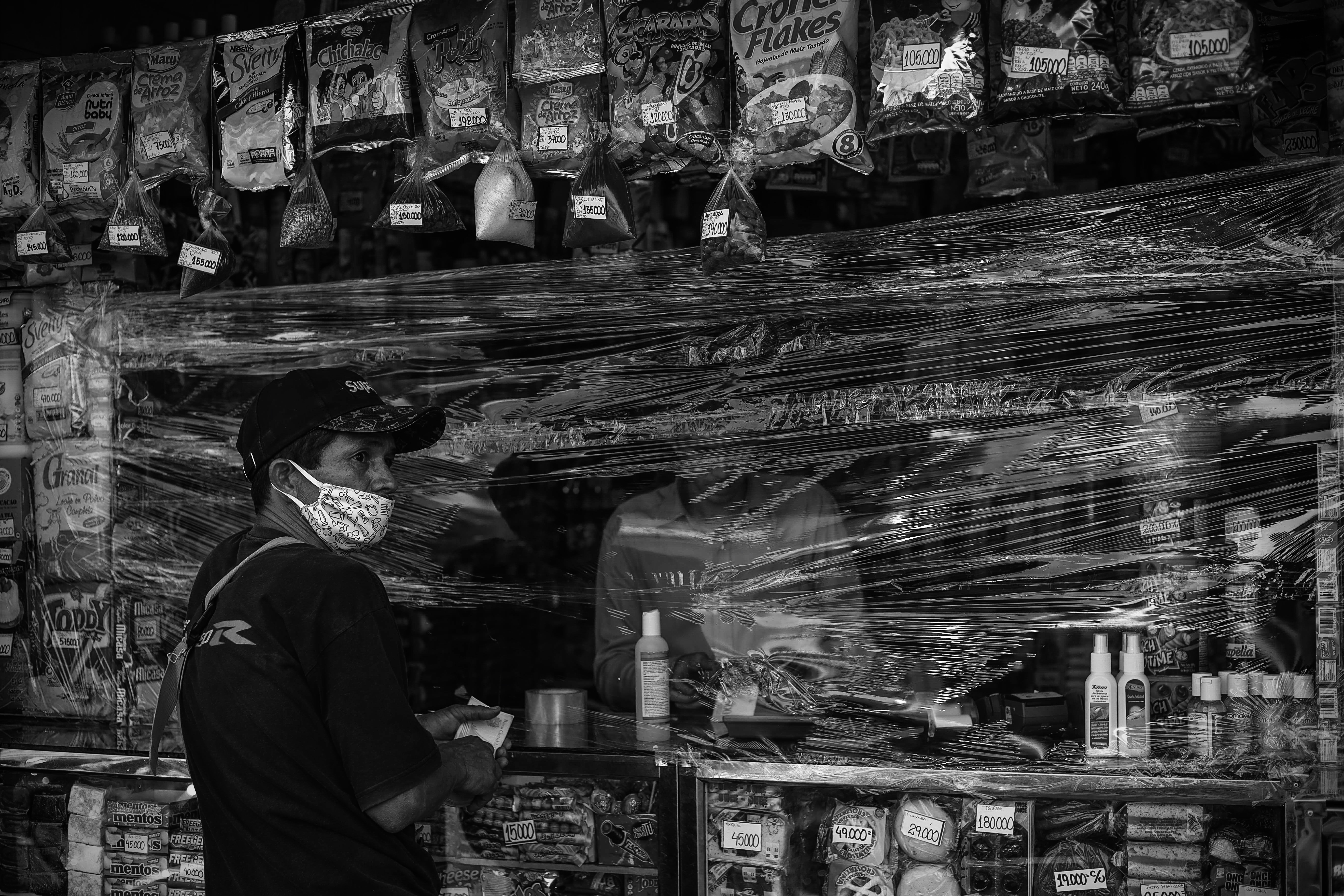 Un joven pretende comprar algo en una tienda cubierta de plástico como medida de precaución contra la propagación del nuevo coronavirus COVID-19 en Caracas. Venezuela podría padecer una epidemia sin precedentes (AFP)