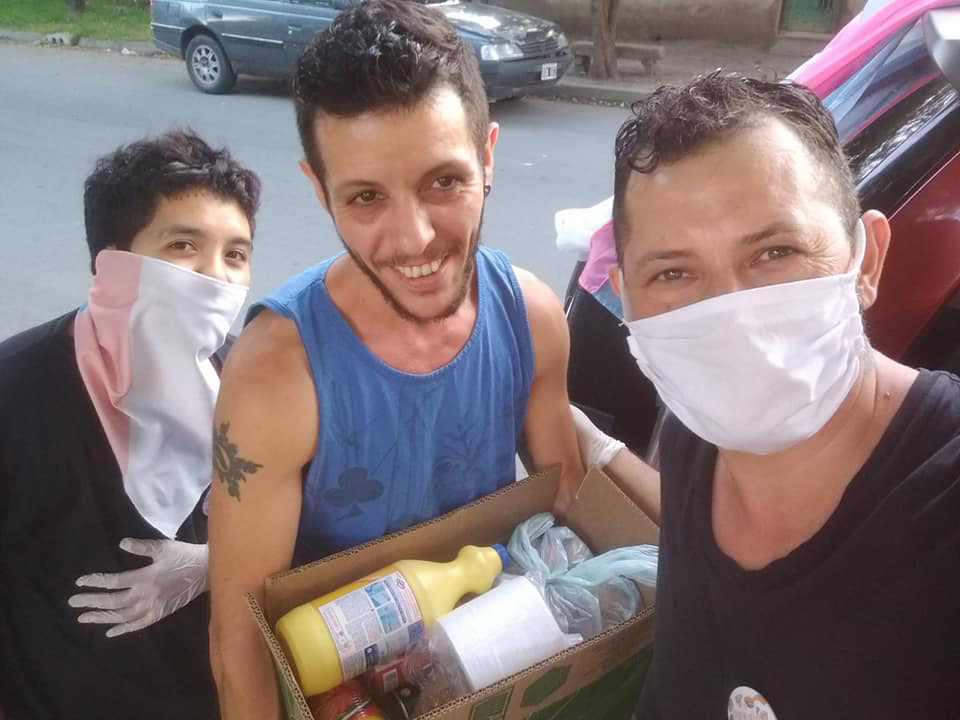 Santiago Merlo (a la derecha) junto a otros varones trans reparten alimentos para asistir a sus compañeros.