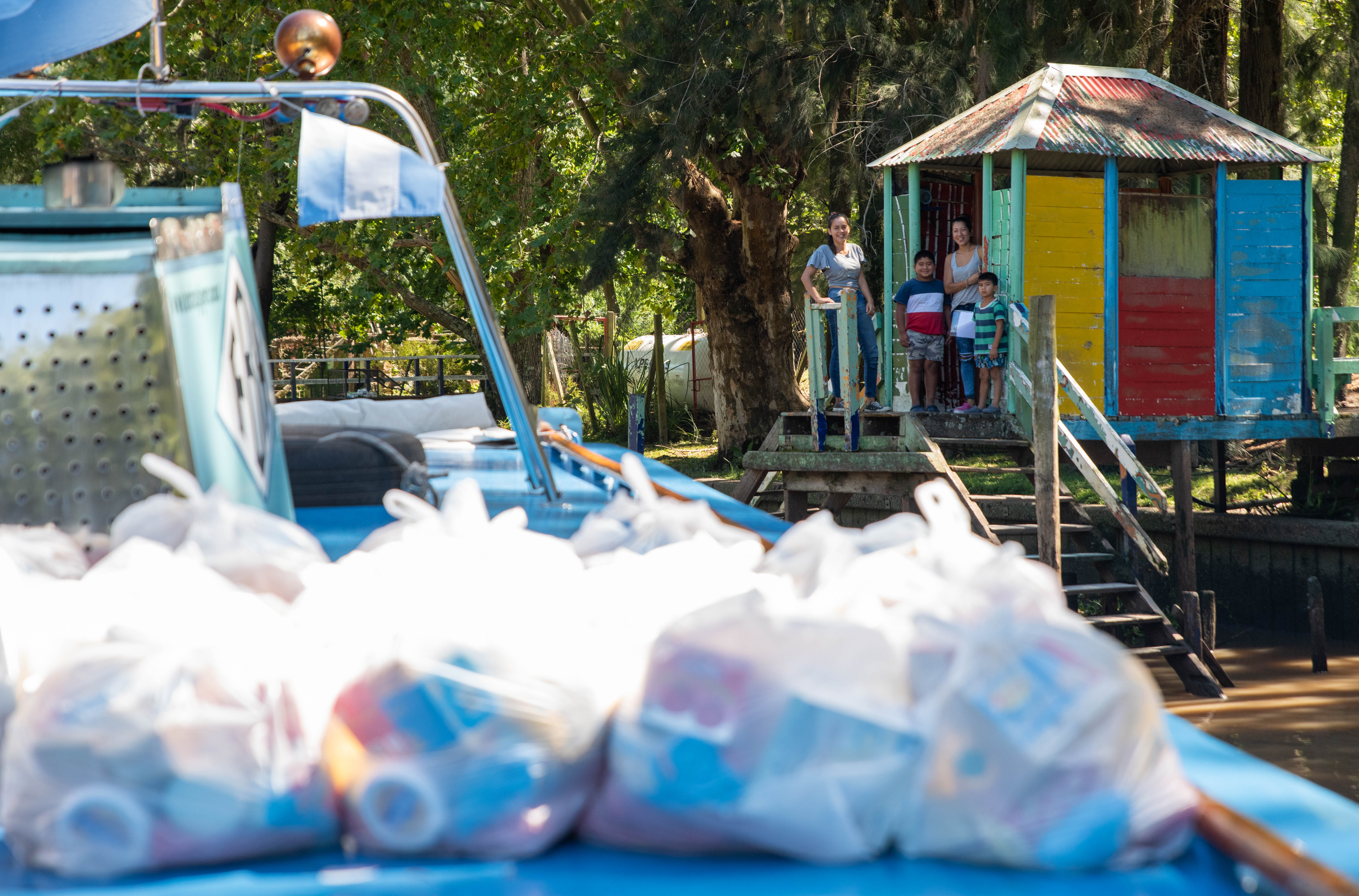 Una familia espera en el muelle, frente a su casa, que los docentes lleguen a entregarles los bolsones de alimentos y libros escolares. (Foto: Franco Fafasuli)