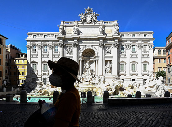 Una turista con un barbijo frente a la fontana di Trevi en el centro de Roma, el primer día del cierre de casi todas las actividades de país. (Foto de Vincenzo PINTO / AFP)
