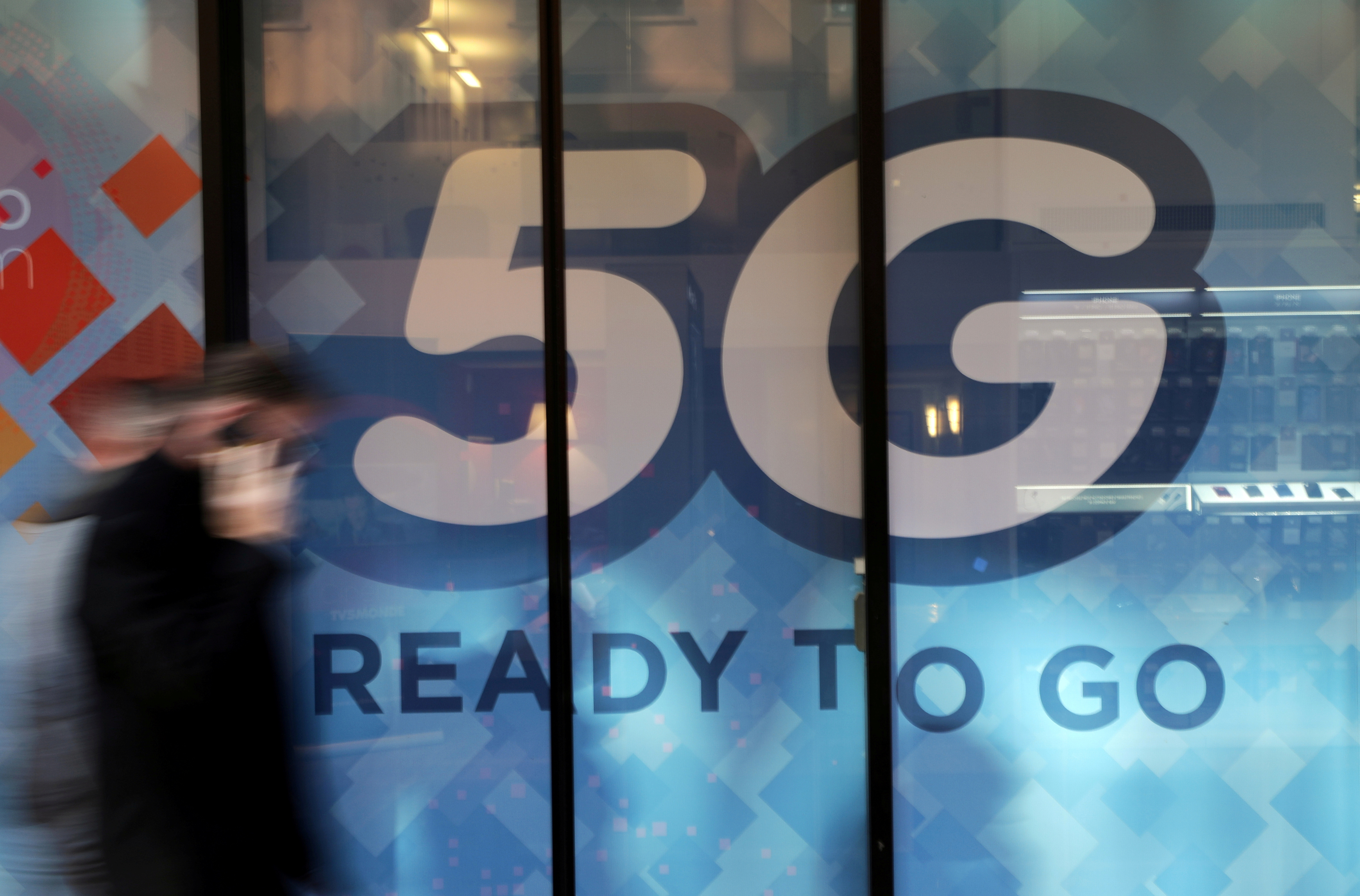 Un hombre camina delante de un logo de 5G en Mónaco (REUTERS/Eric Gaillard)