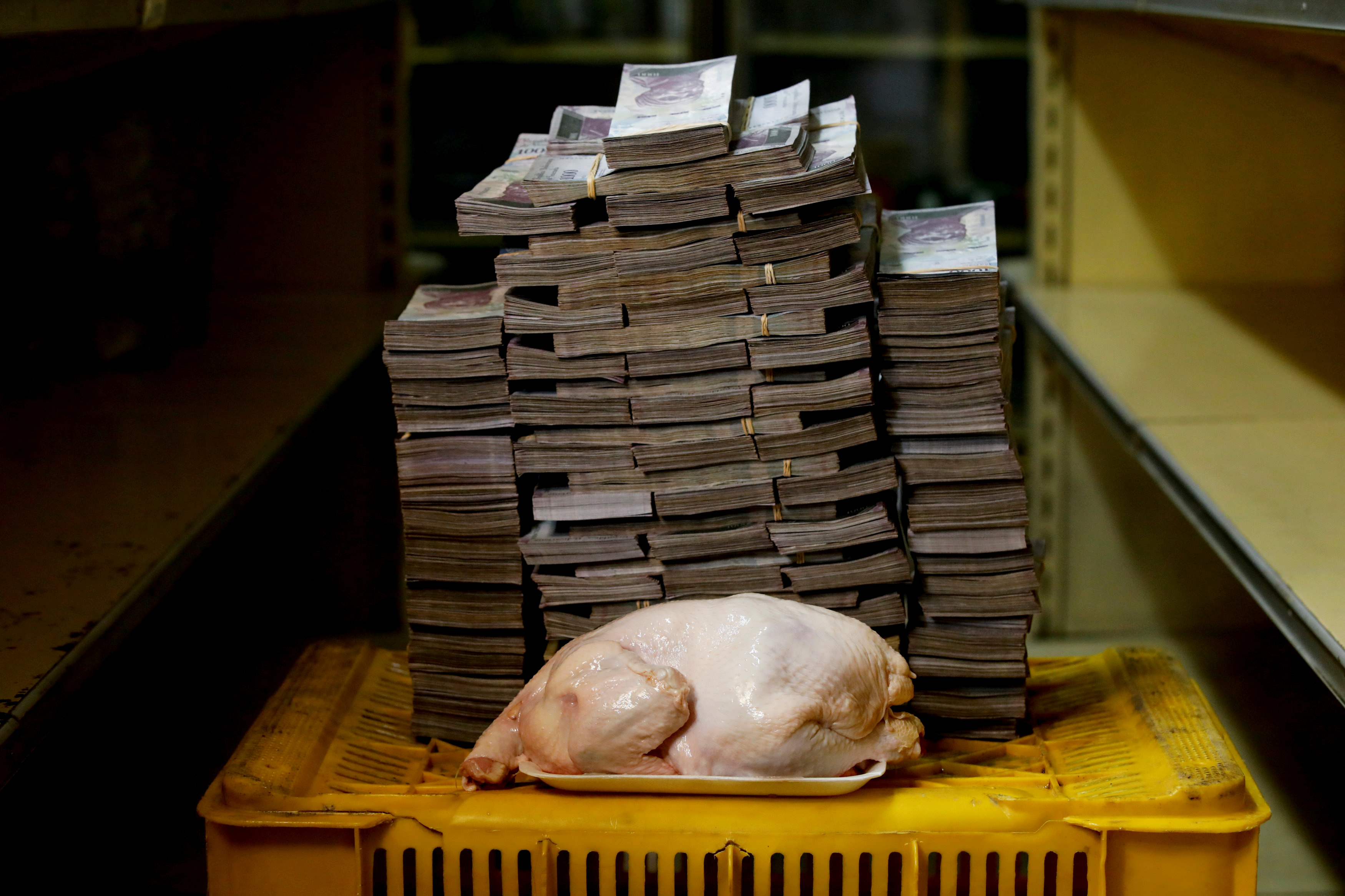 Un pollo de 2,4 kg es fotografiado junto a 14.600.000 bolívares, su precio y el equivalente a 2,22 USD, en un mini-mercado en Caracas, Venezuela, el 16 de agosto de 2018 (REUTERS/Carlos Garcia Rawlins)