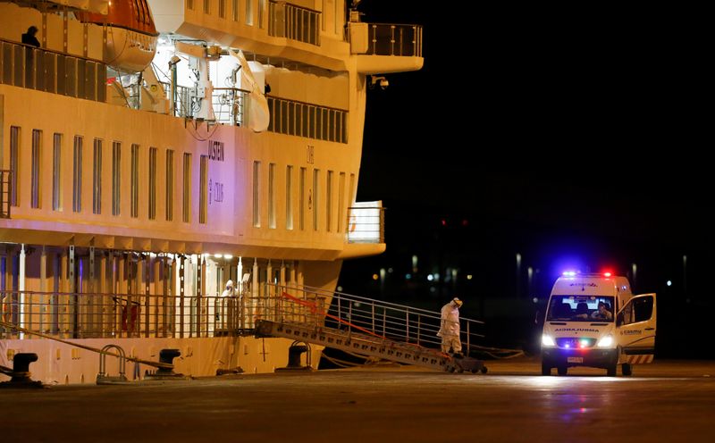 Personal médico espera la salida de los pasajeros del crucero australiano Greg Mortimer en el puerto de Montevideo, que serán trasladados al aeropuerto local para abordar un vuelo rumbo a Melbourne