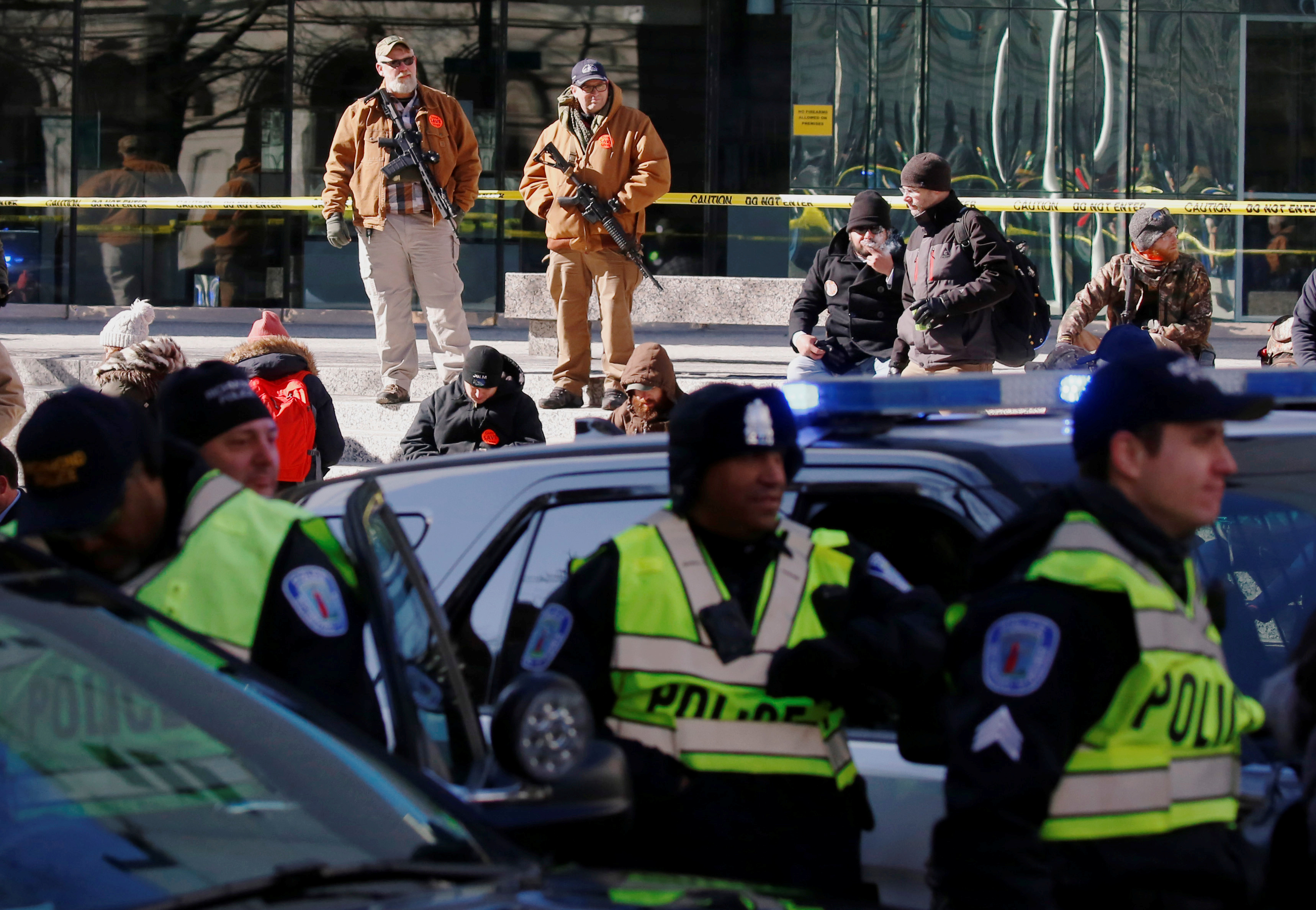 La policía custodia, en primer plano, y se asegura que no ingresen armas al sector frente al Capitolio. Por detrás, dos asistentes con sus AR-15 (REUTERS/Jim Urquhart)