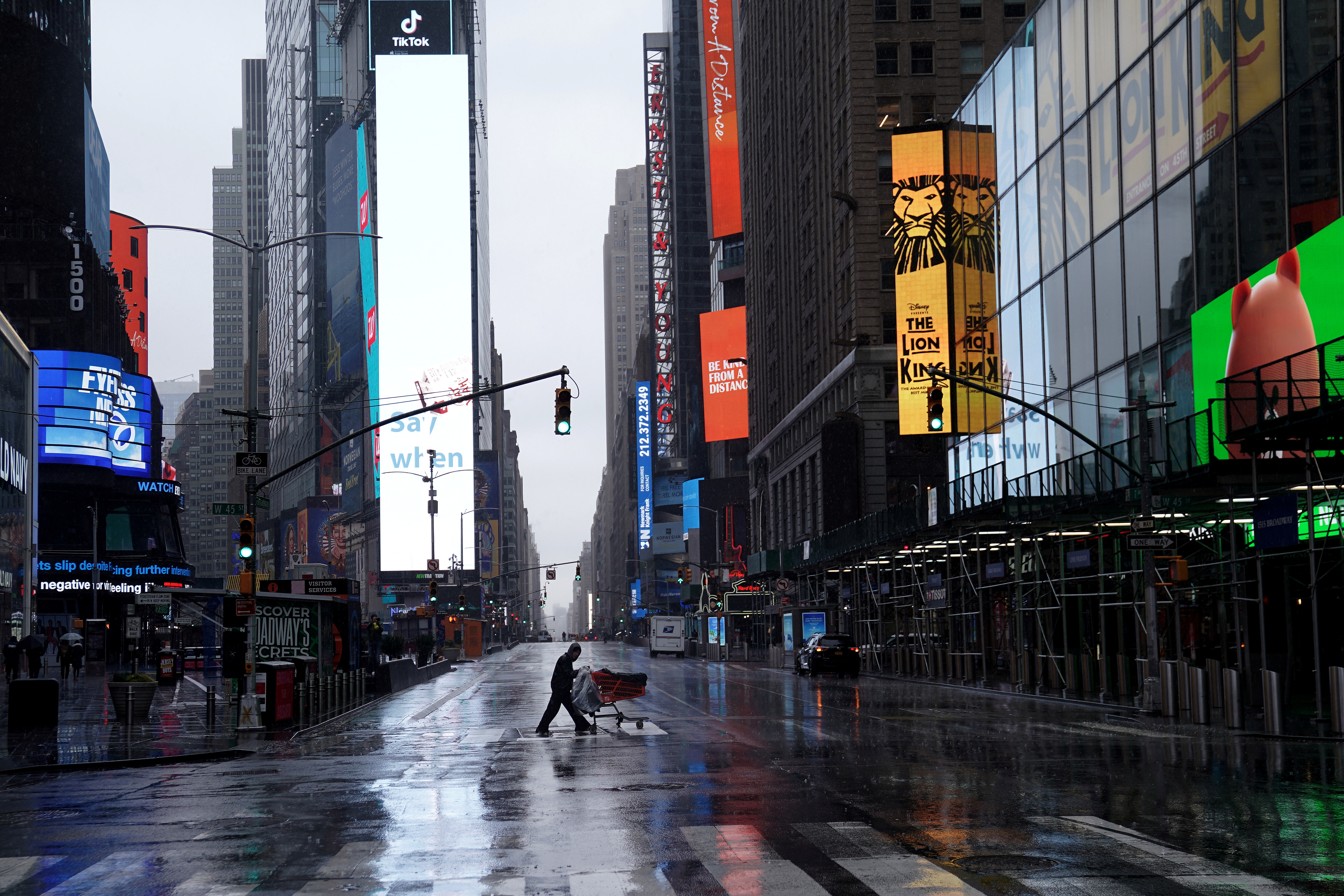 Una persona sin hogar empuja sus pertenencias a través de un Times Square desierto después del brote de la enfermedad por coronavirus (COVID-19). La economía norteamericana está virtualmente detenida, y las alarmas sobre las consecuencias comienzan a sonar (Reuters)